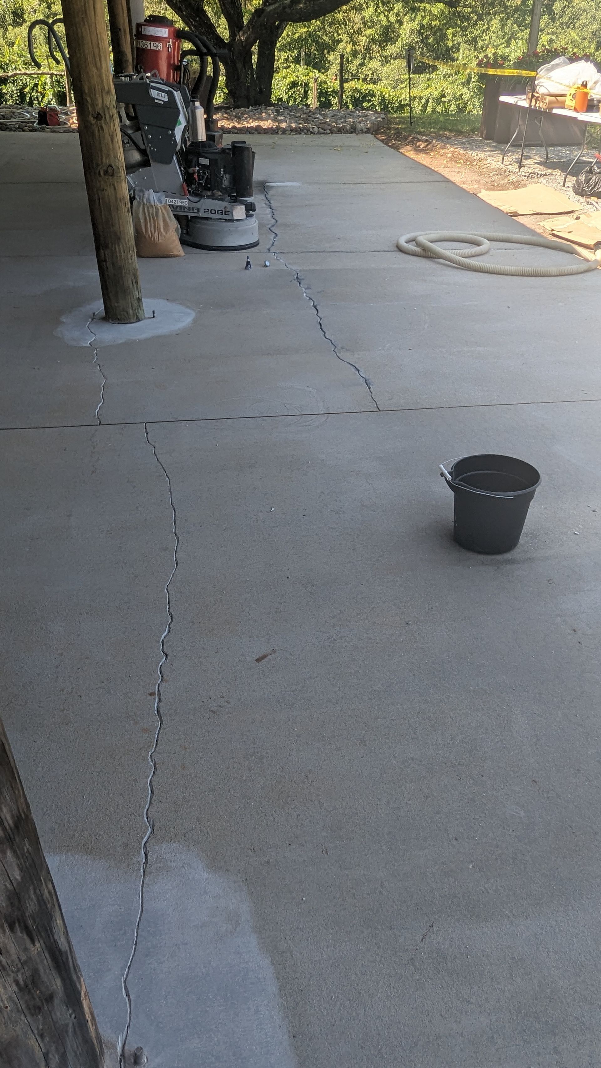A bucket is sitting on a concrete floor next to a machine.