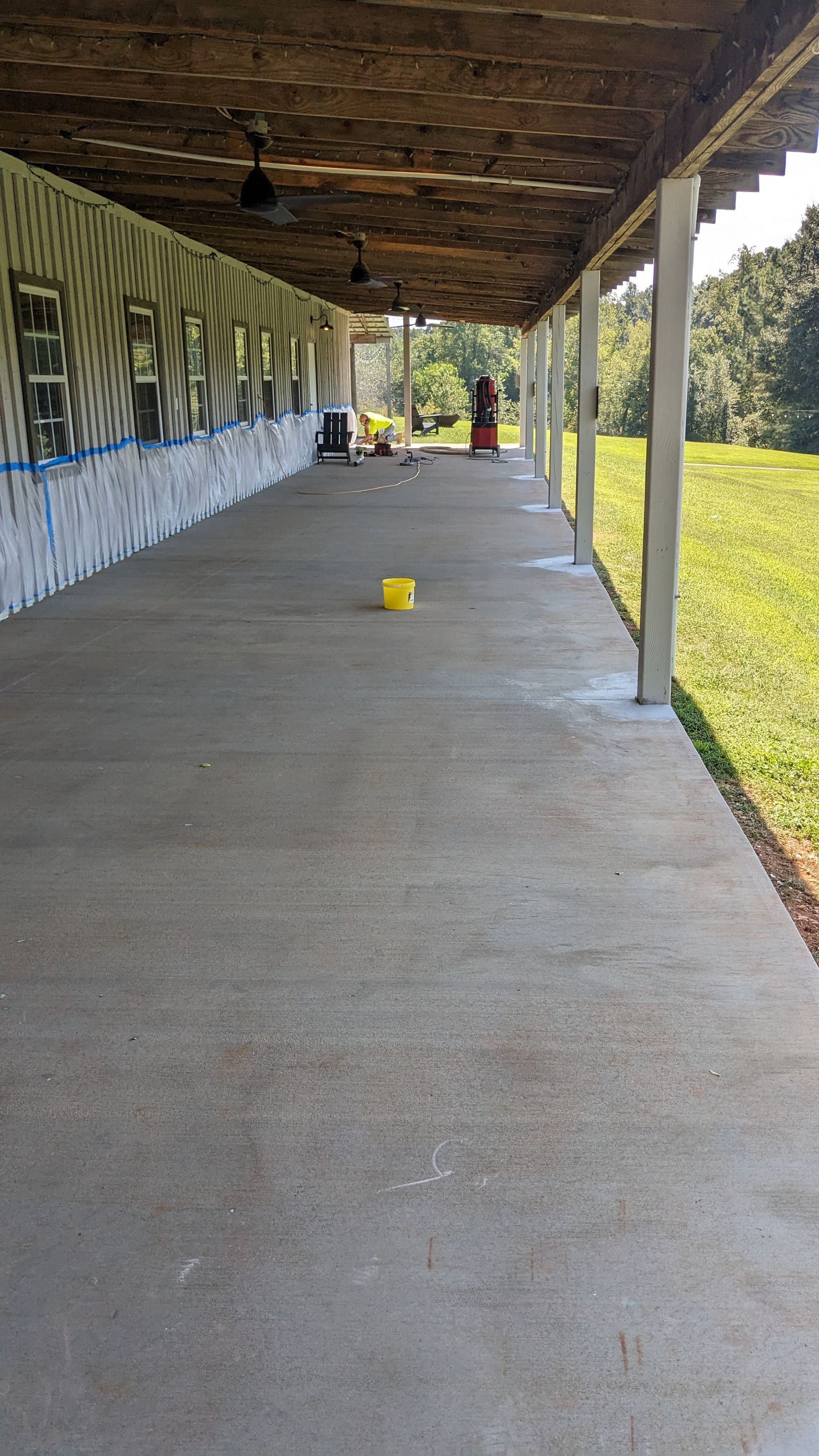 A long concrete walkway with a yellow bucket in the middle of it.