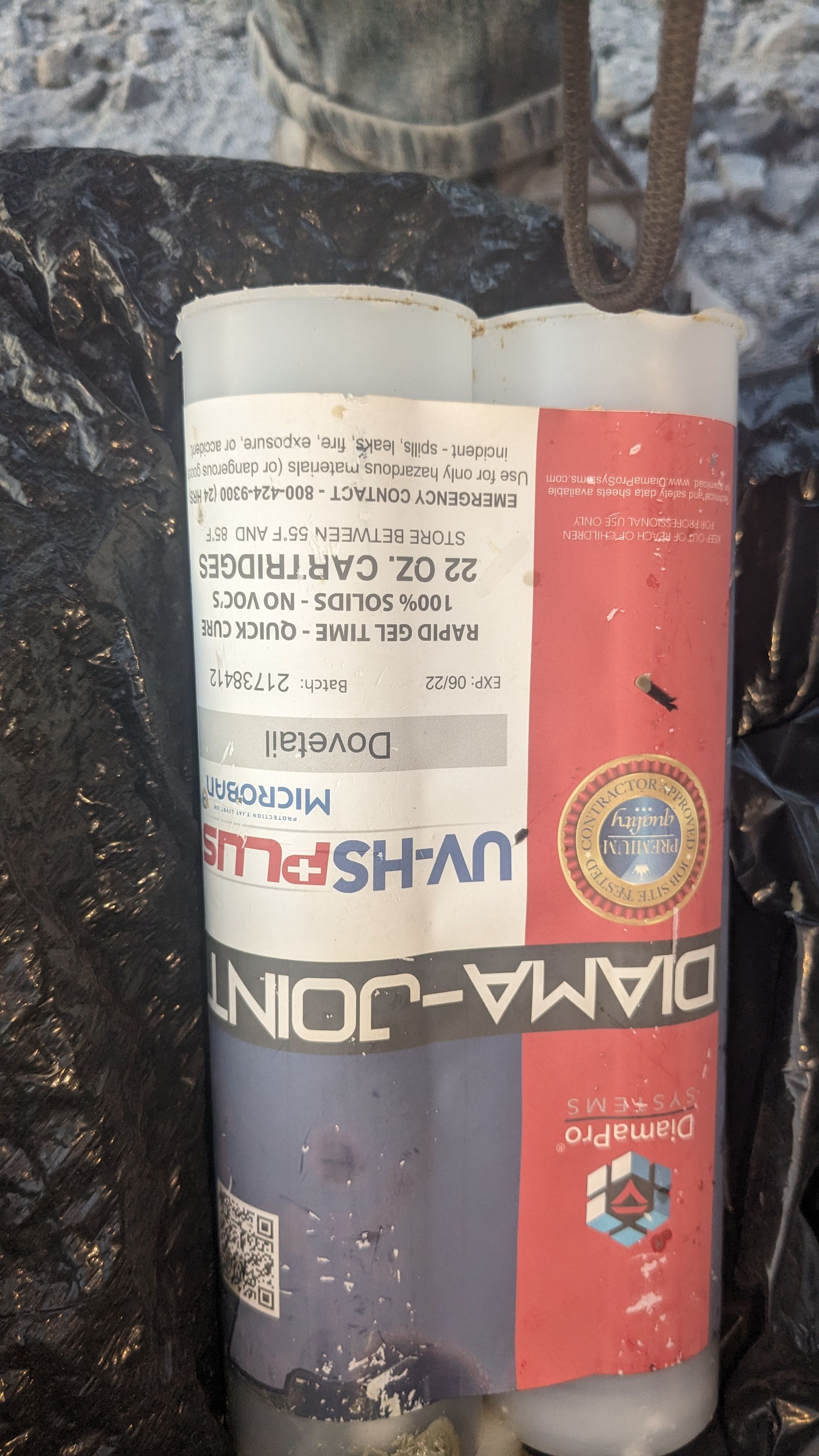 A bottle of diamond joint is sitting on a black tarp.