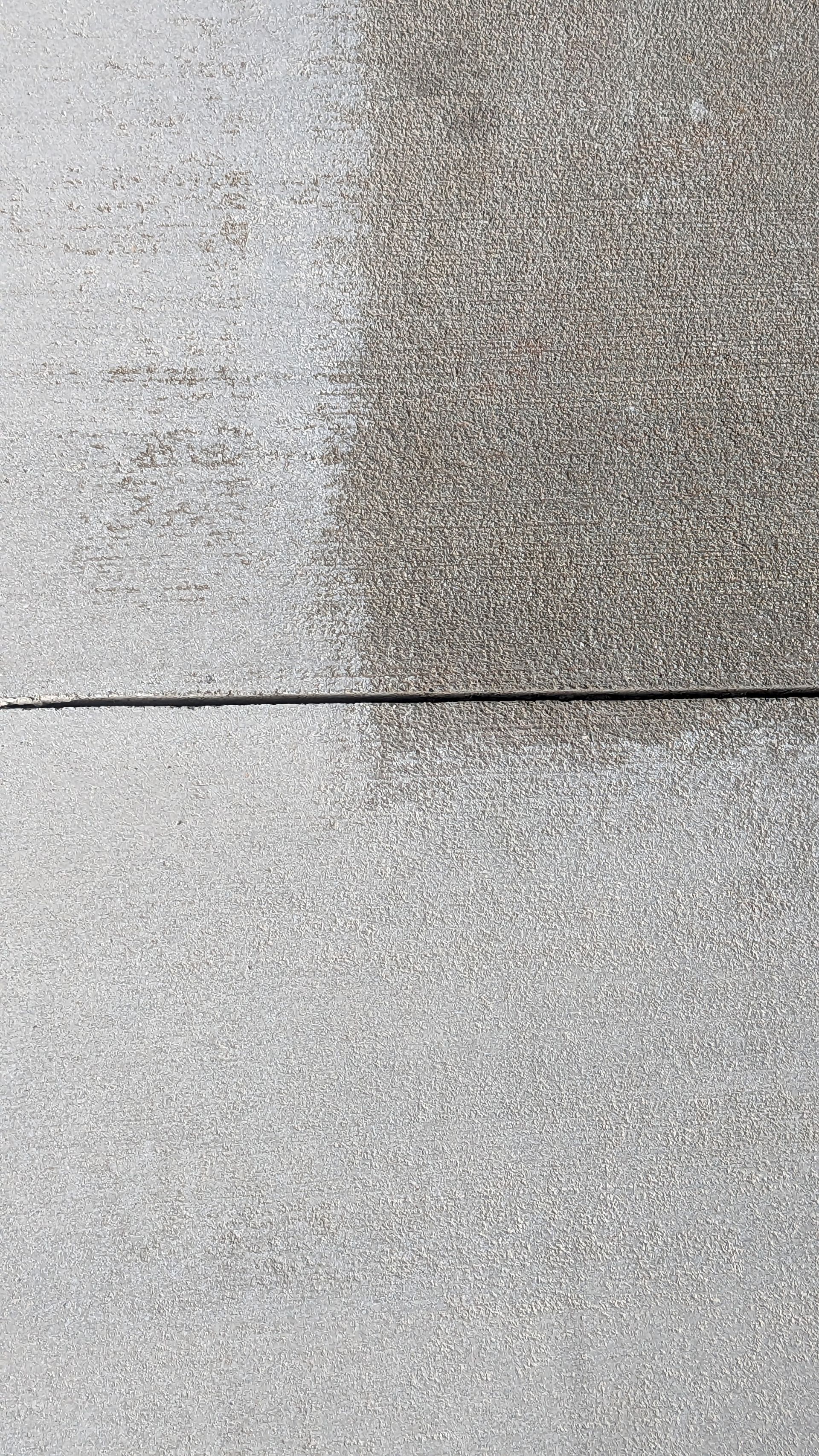 A close up of a concrete surface with one side being clean and the other being dirty.