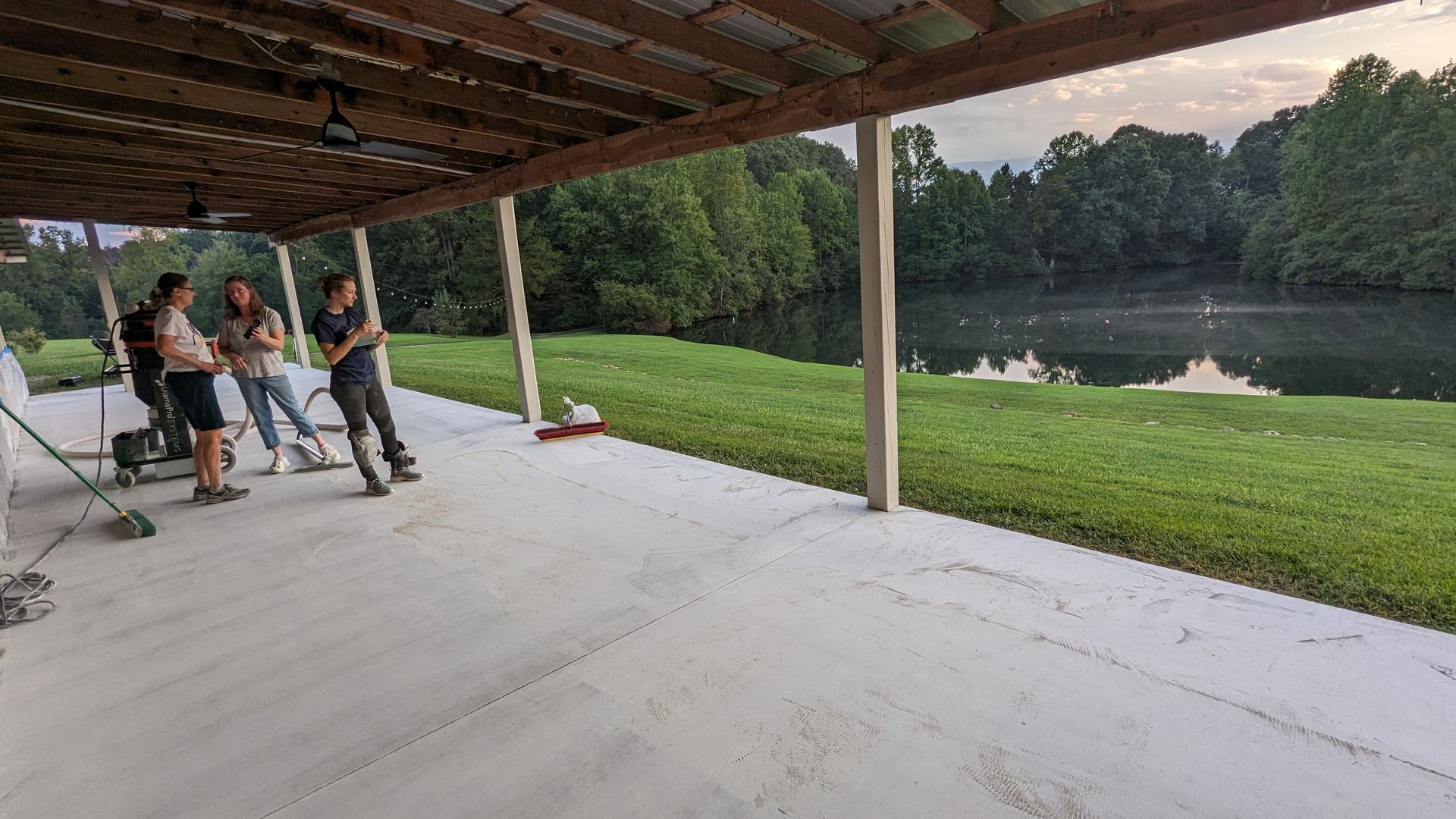A group of people are standing on a porch overlooking a lake.