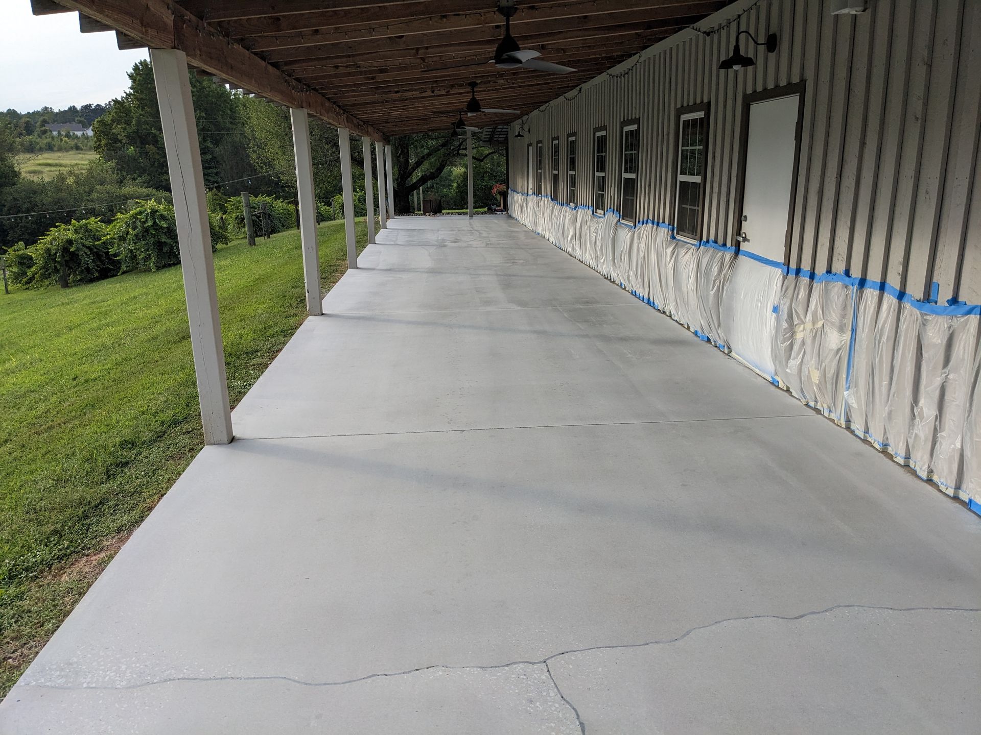 A long concrete walkway leading to a building with a ceiling fan.