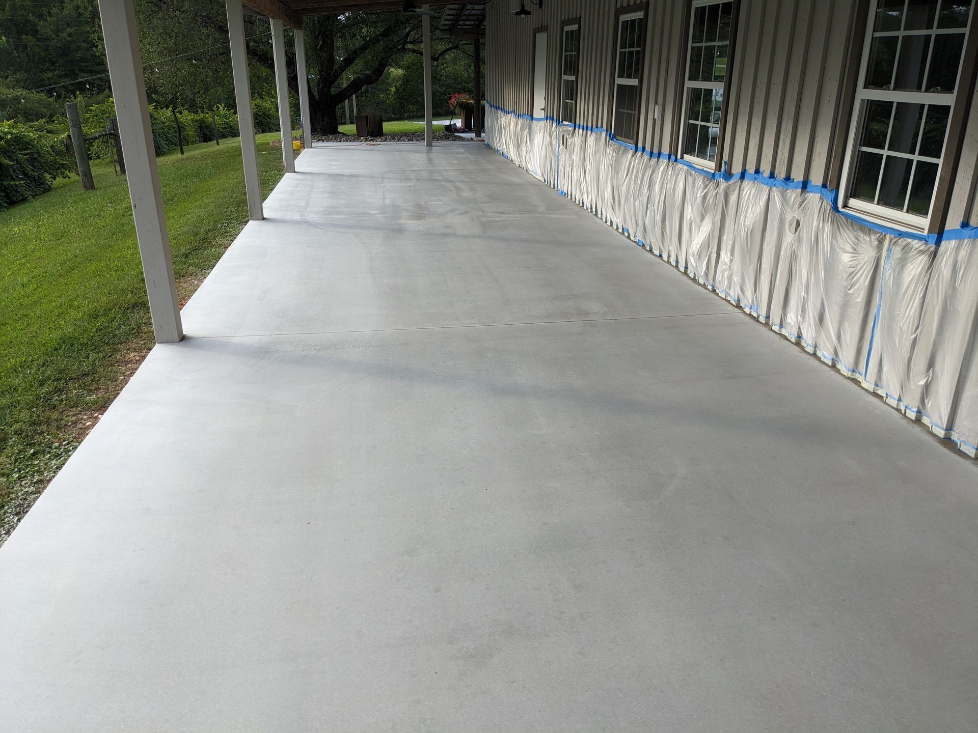 A concrete porch with a wooden house in the background.