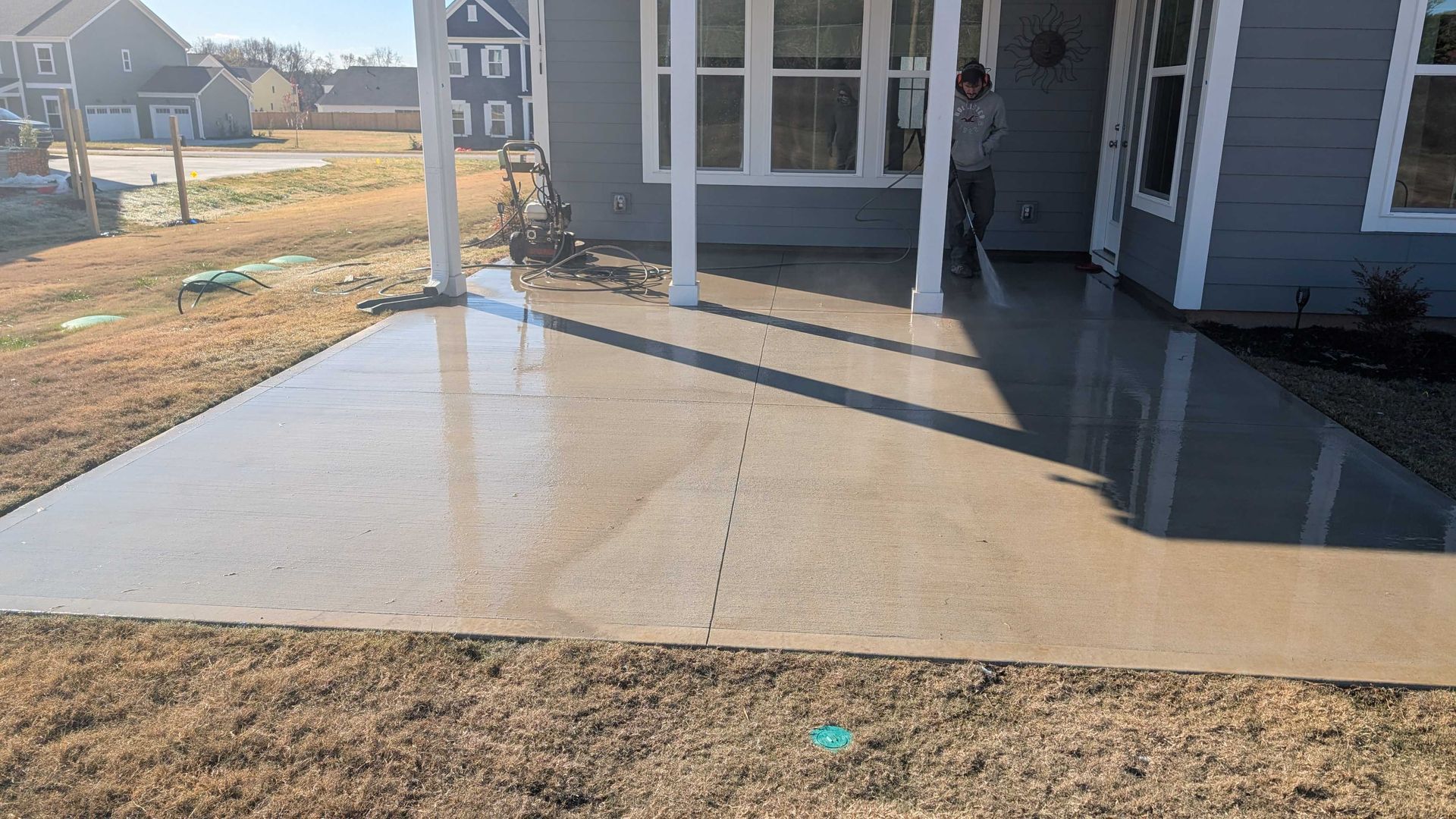 A man is standing on a concrete patio in front of a house.