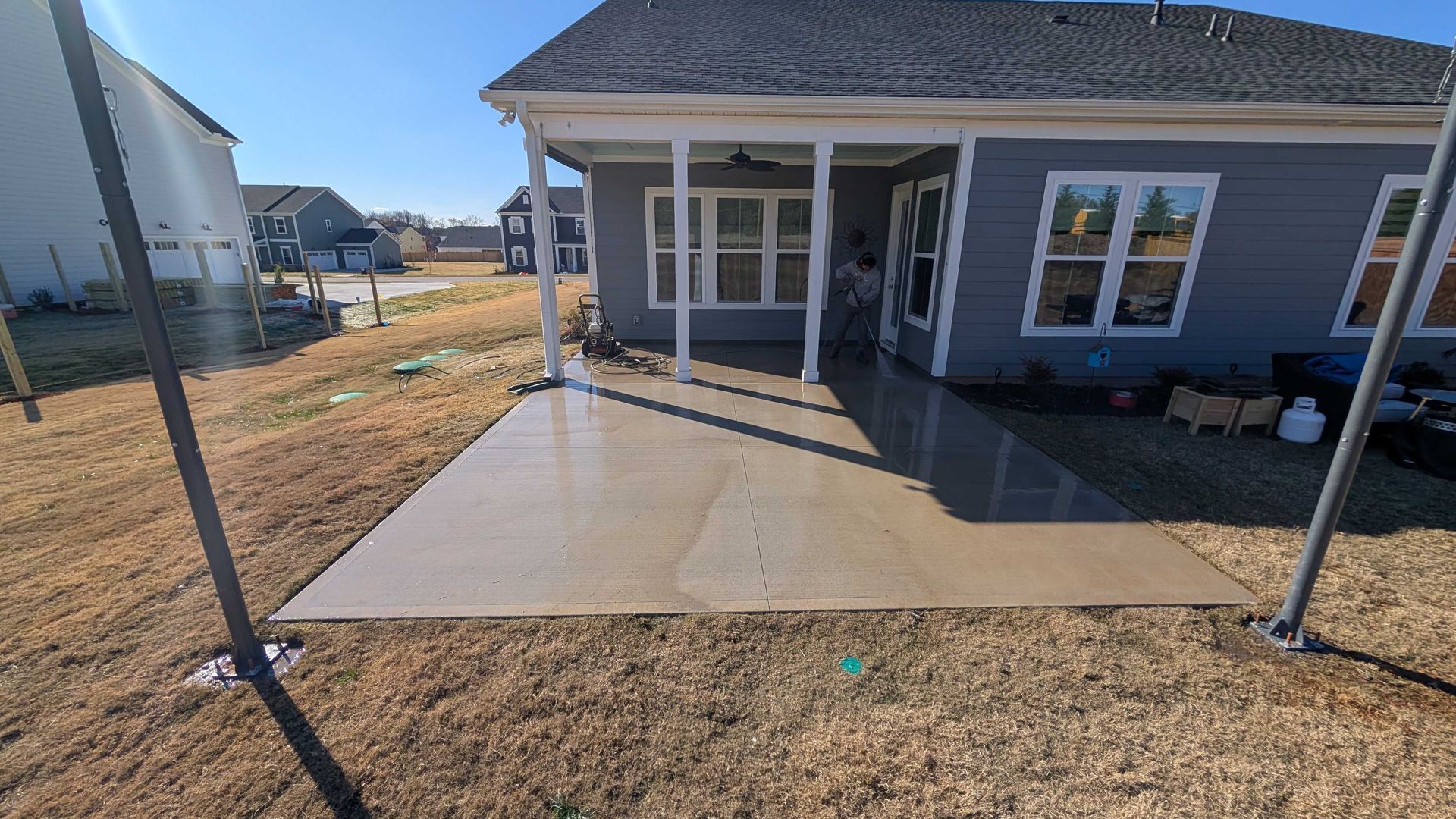 A concrete patio in front of a house with a porch.