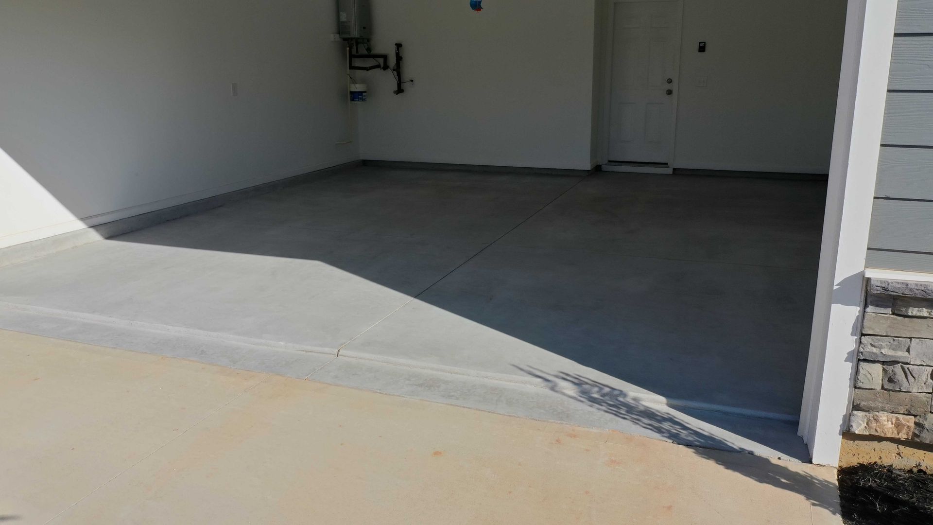 A concrete driveway in a garage next to a house.