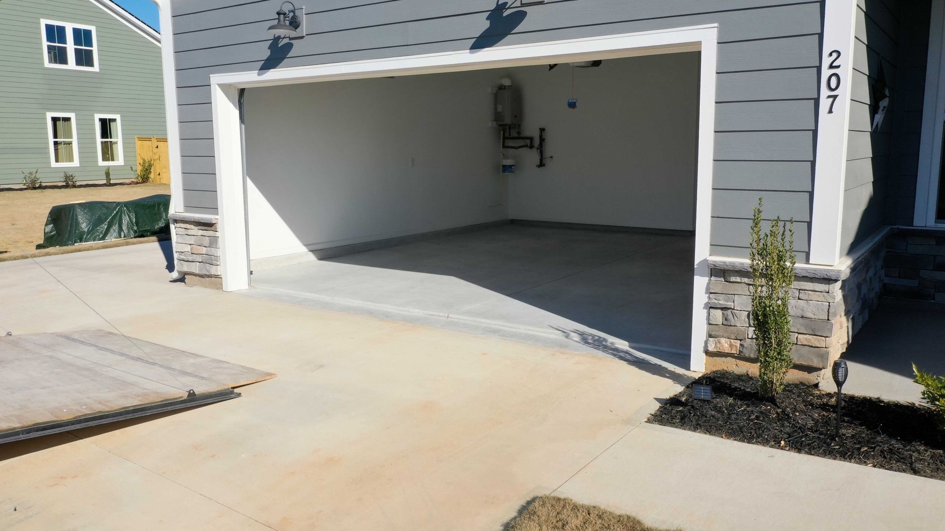 A garage with the door open in front of a house.