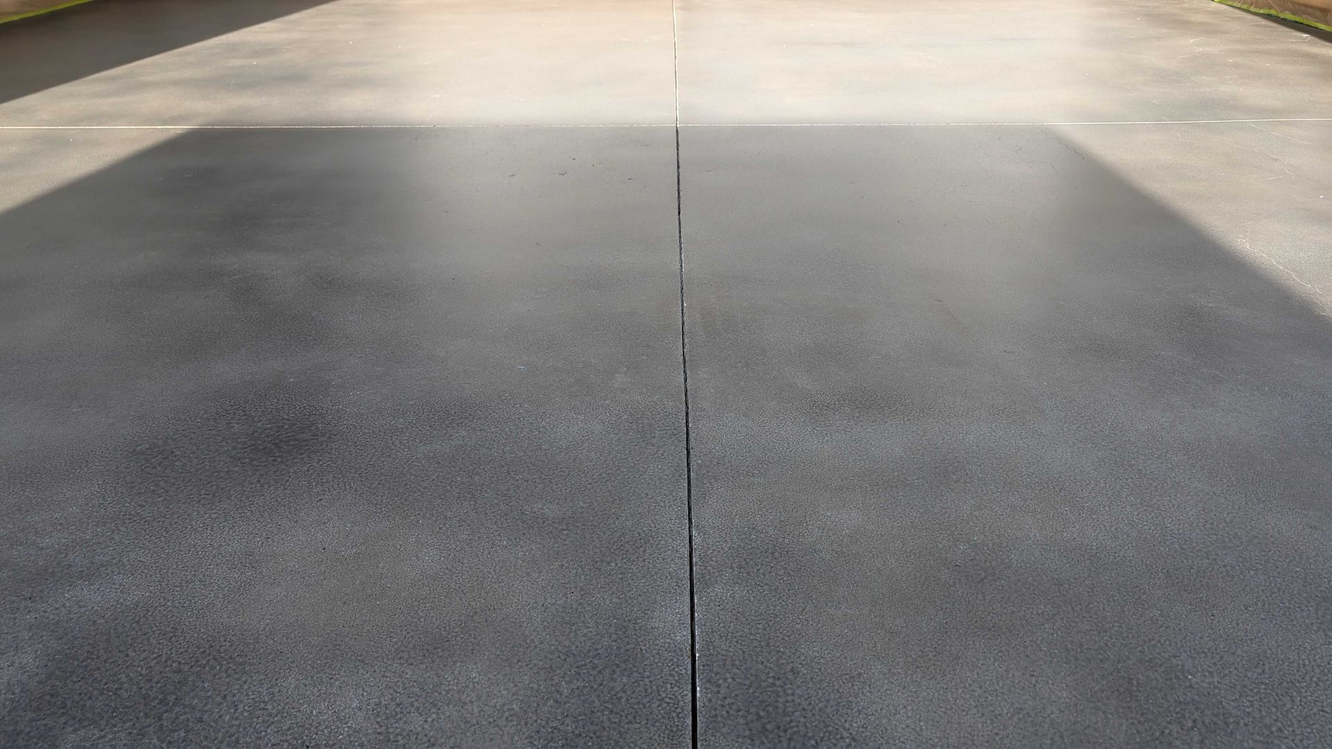 A close up of a concrete driveway with a shadow on it.