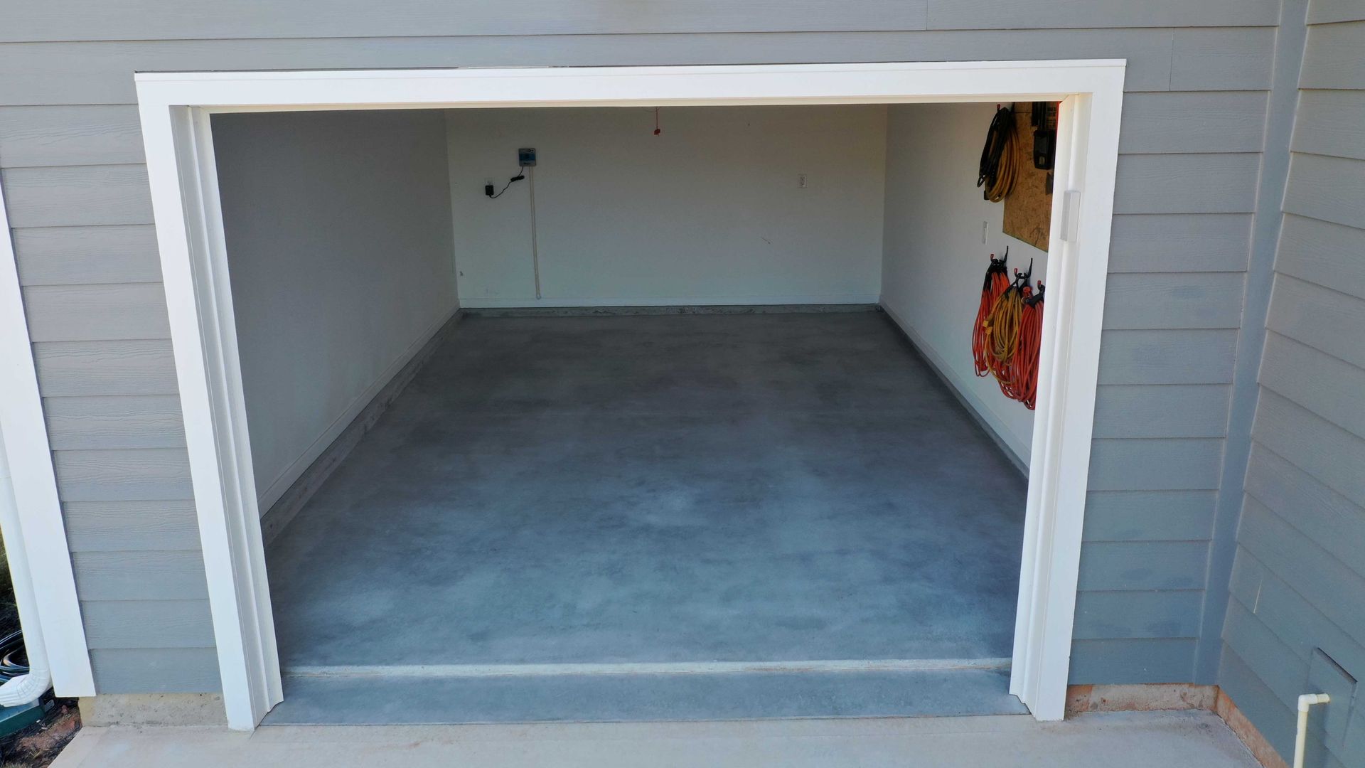 A garage with a door open and a concrete floor.