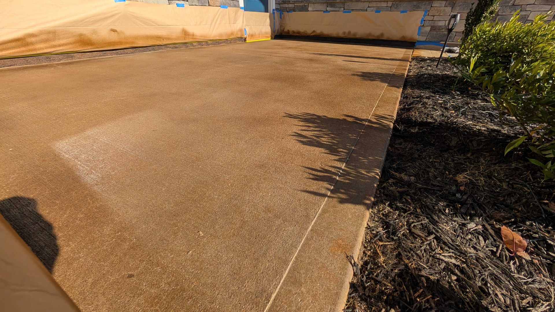 Freshly stained and sealed concrete driveway with a warm brown finish in Greenville, SC.