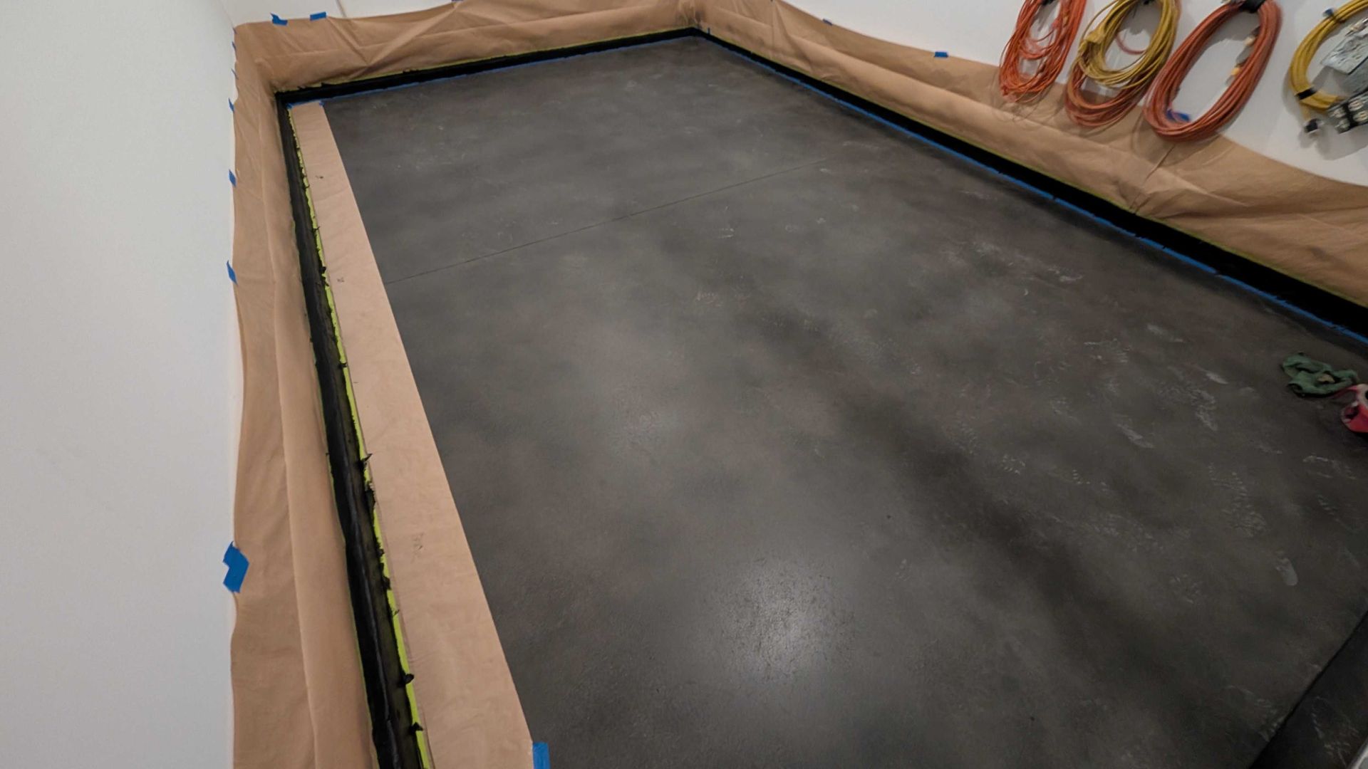 A concrete floor is being painted in a room.