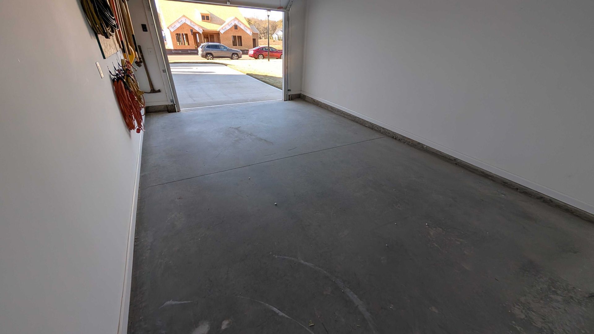An empty garage with a car parked in the driveway.