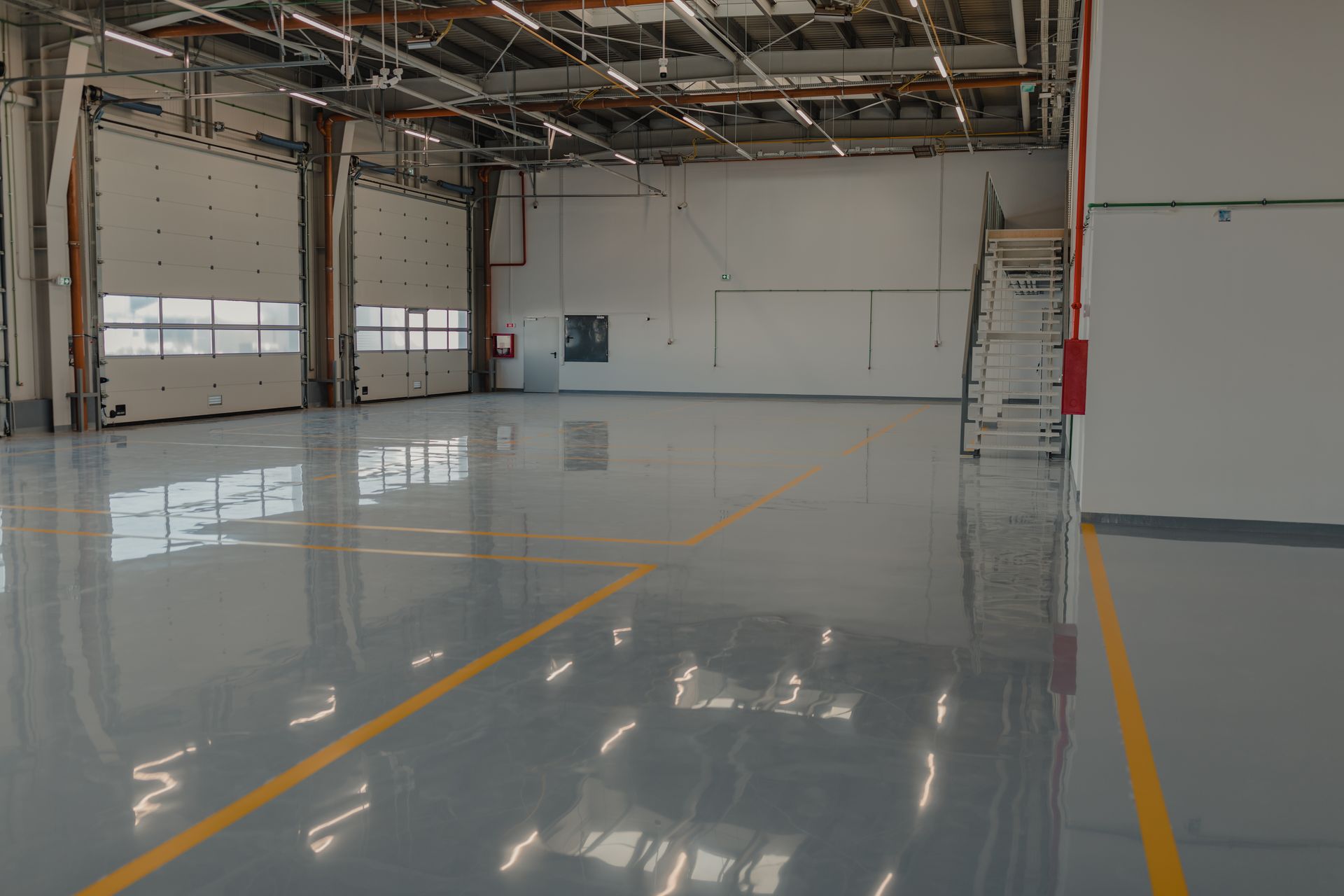 A large empty warehouse with a shiny floor and a yellow line on the floor.