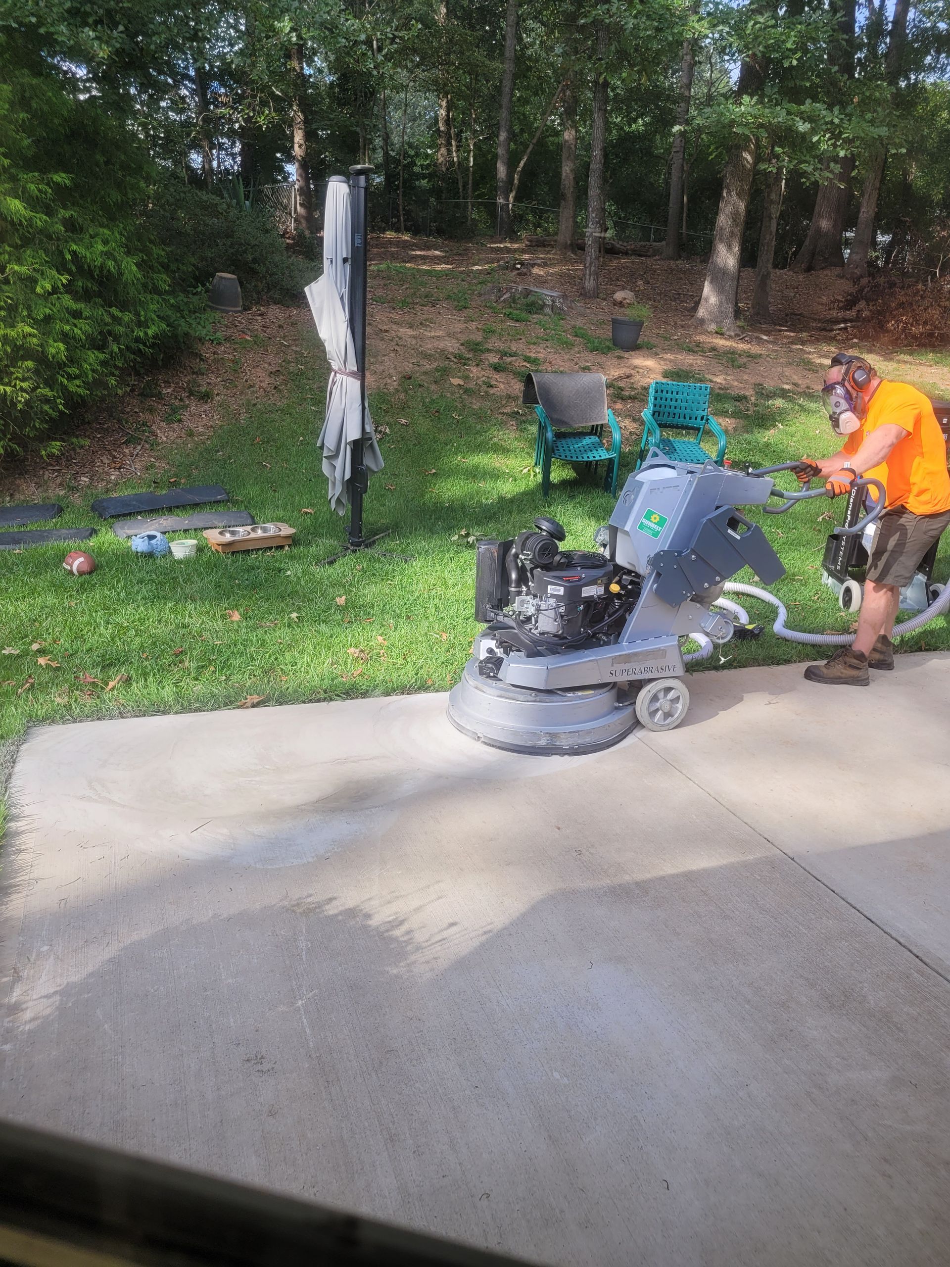 A man is using a machine to clean a concrete patio.