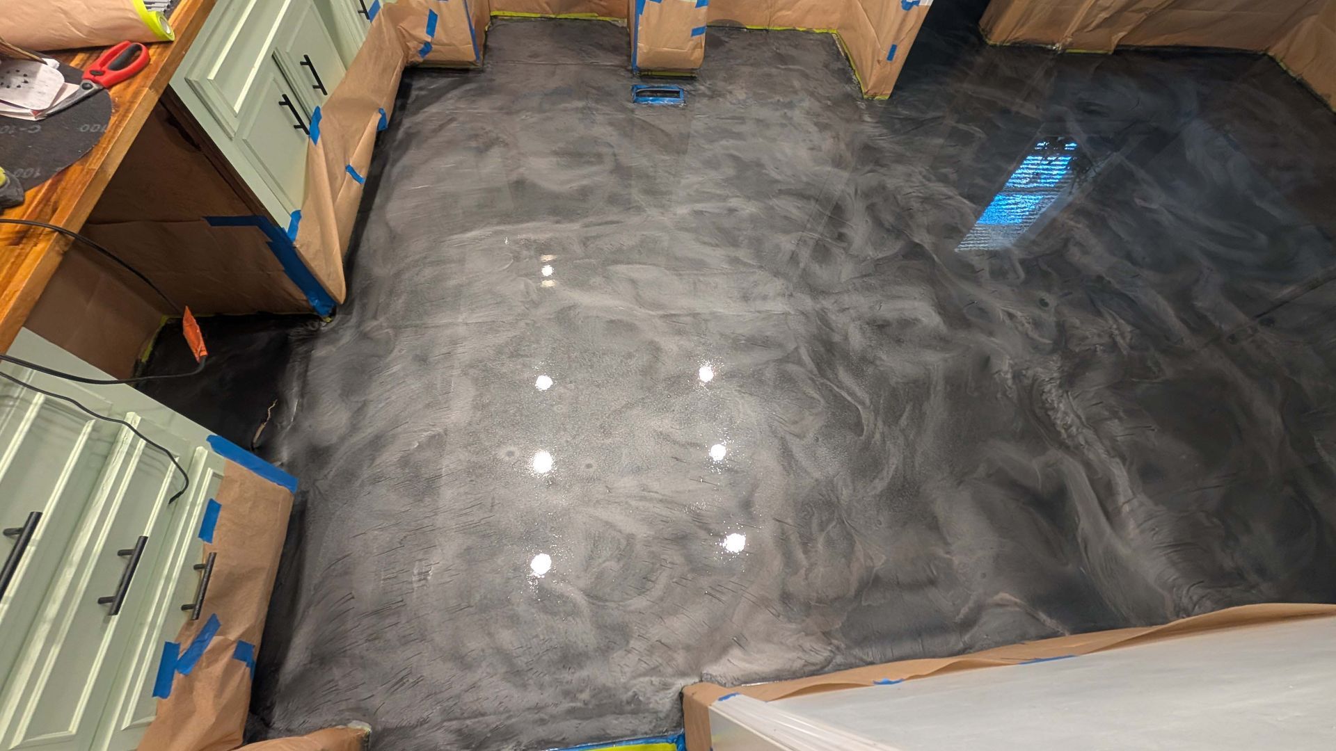 A kitchen with a shiny metallic floor and cabinets.