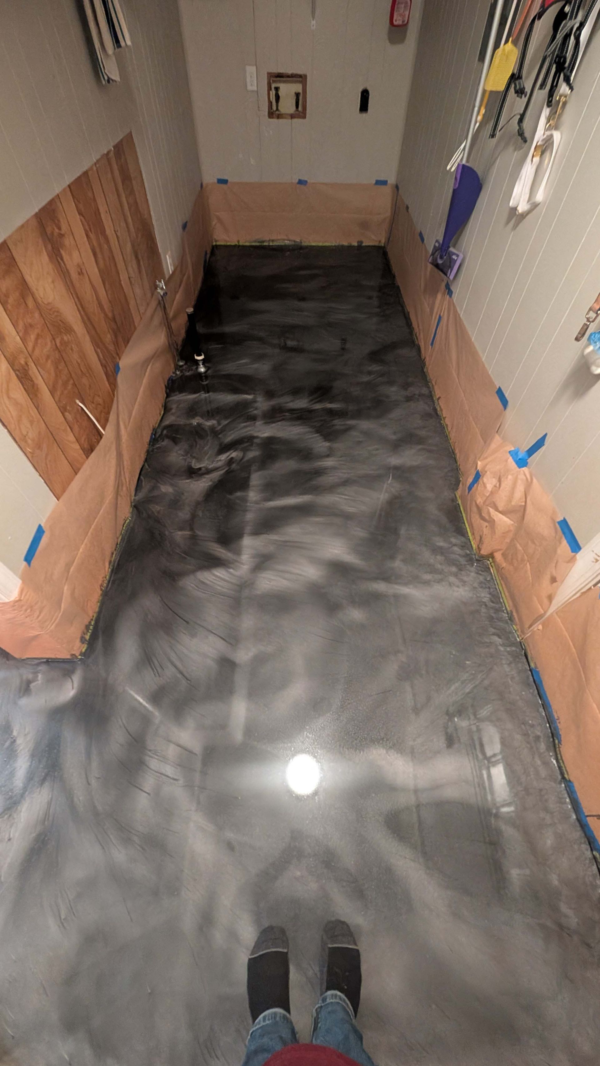 A person is standing on a shiny metallic floor in a room.