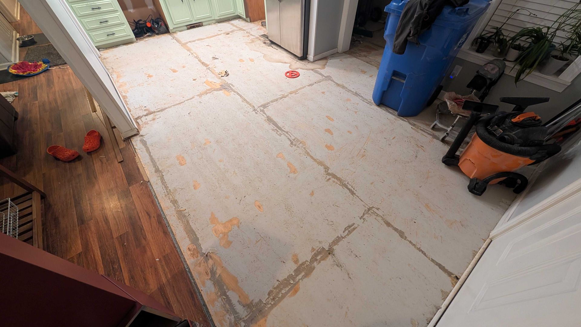 A room with a dirty floor and a vacuum cleaner.