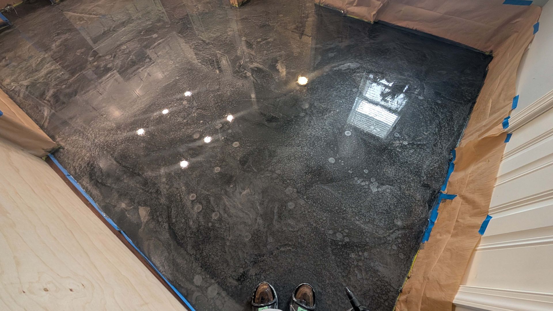 A person is standing on a shiny black concrete floor.