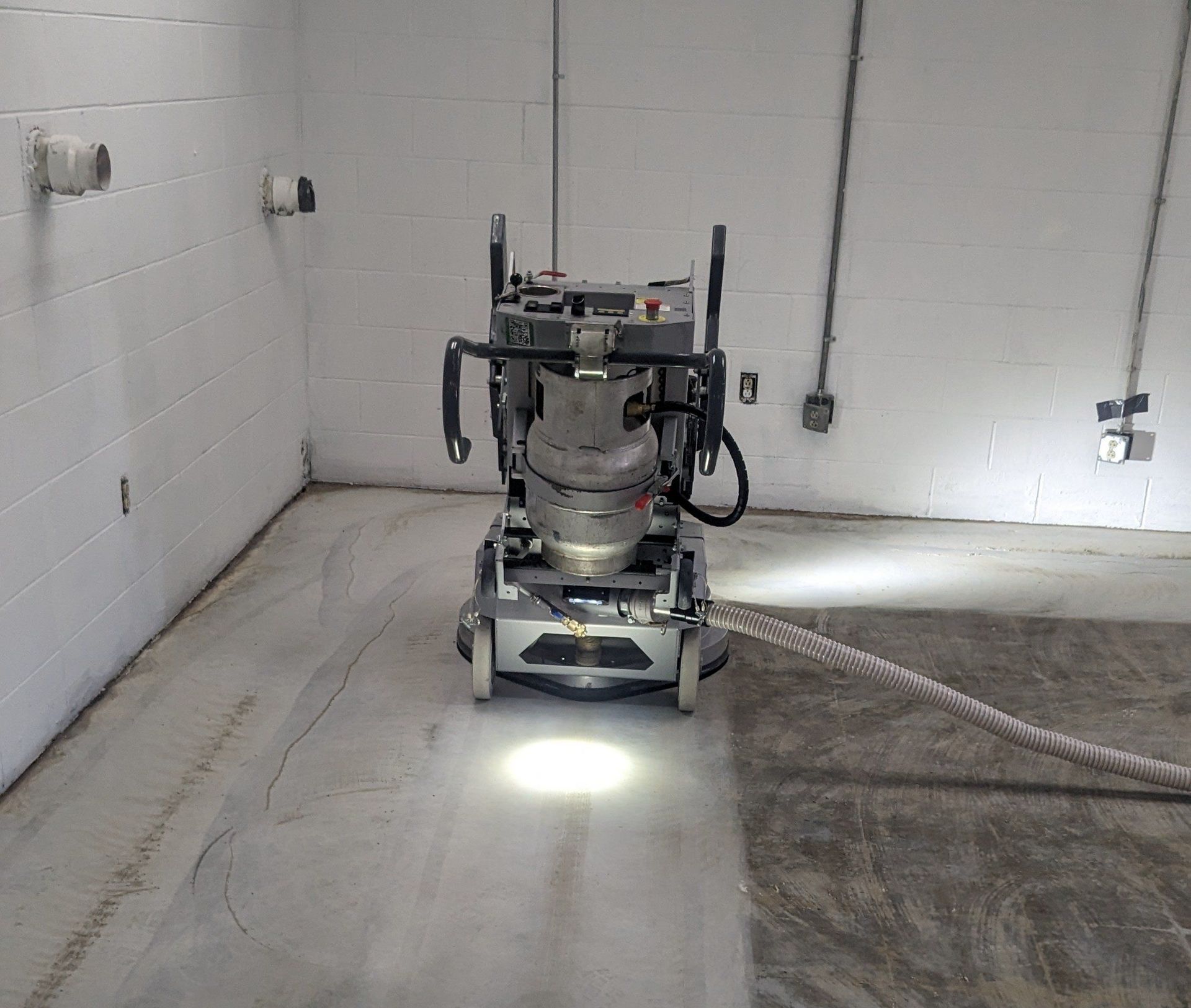 A machine is grinding a concrete floor in a room.