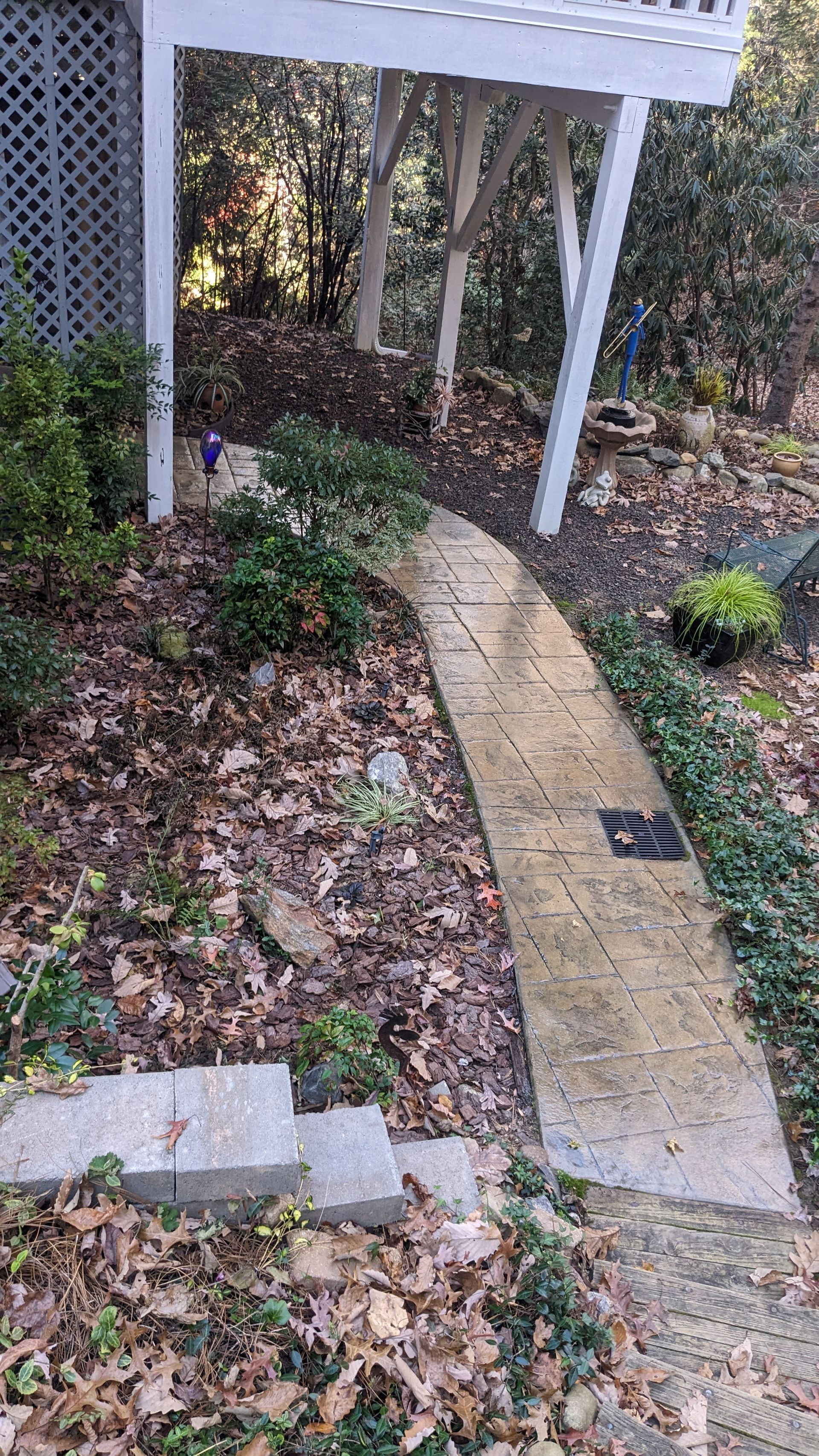 A concrete walkway leading to a house in the woods.