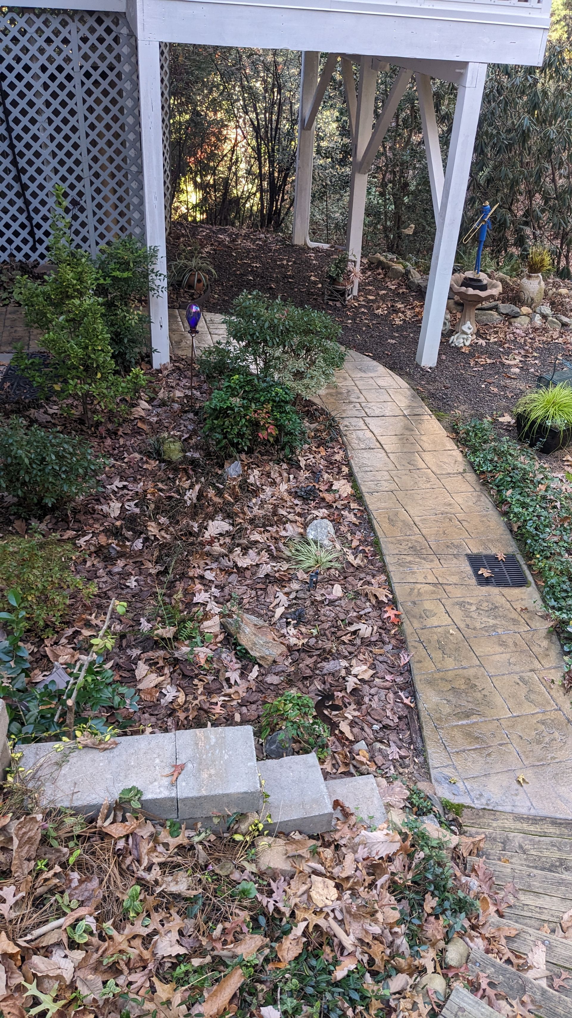 A concrete walkway leading to a white pergola in a garden.