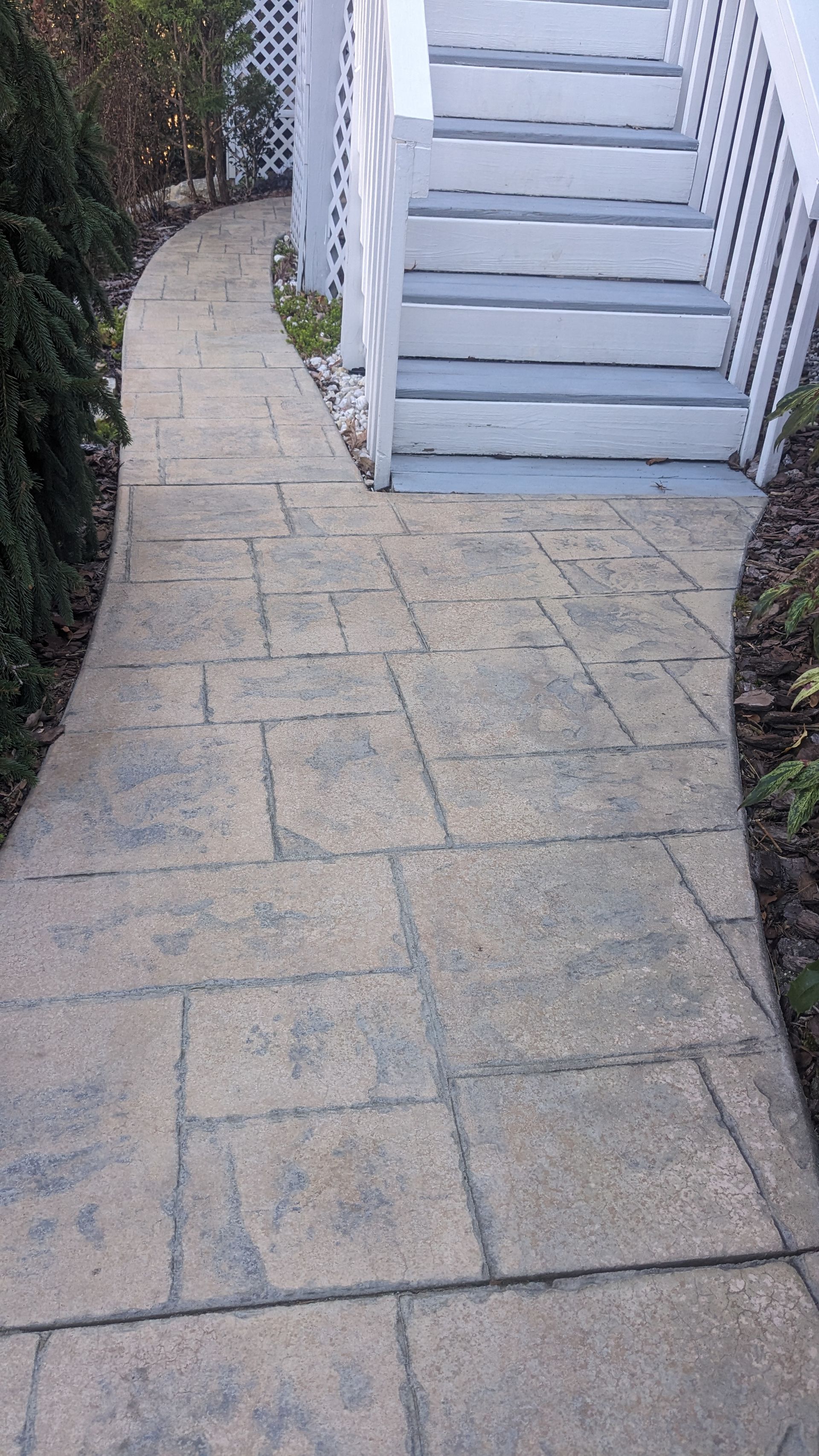 A stone walkway leading to a set of white stairs.