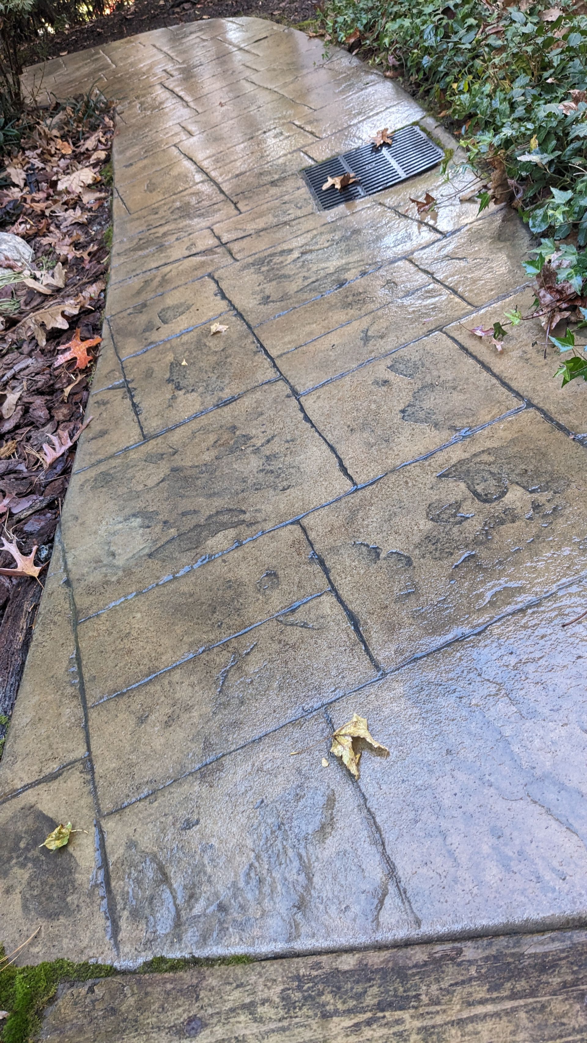 A concrete walkway with a door mat on the side of it.