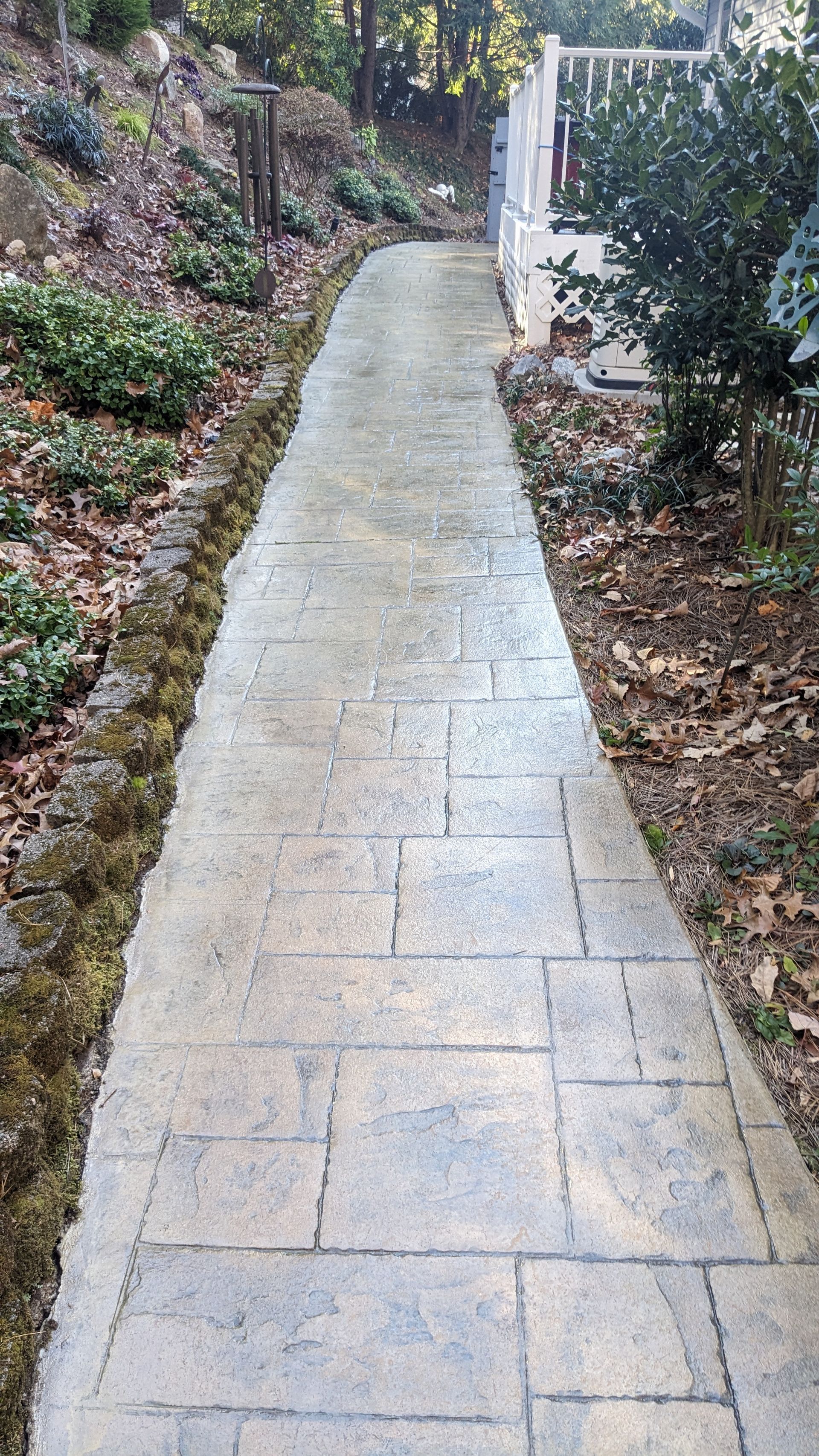 A concrete walkway leading to a house in the woods.