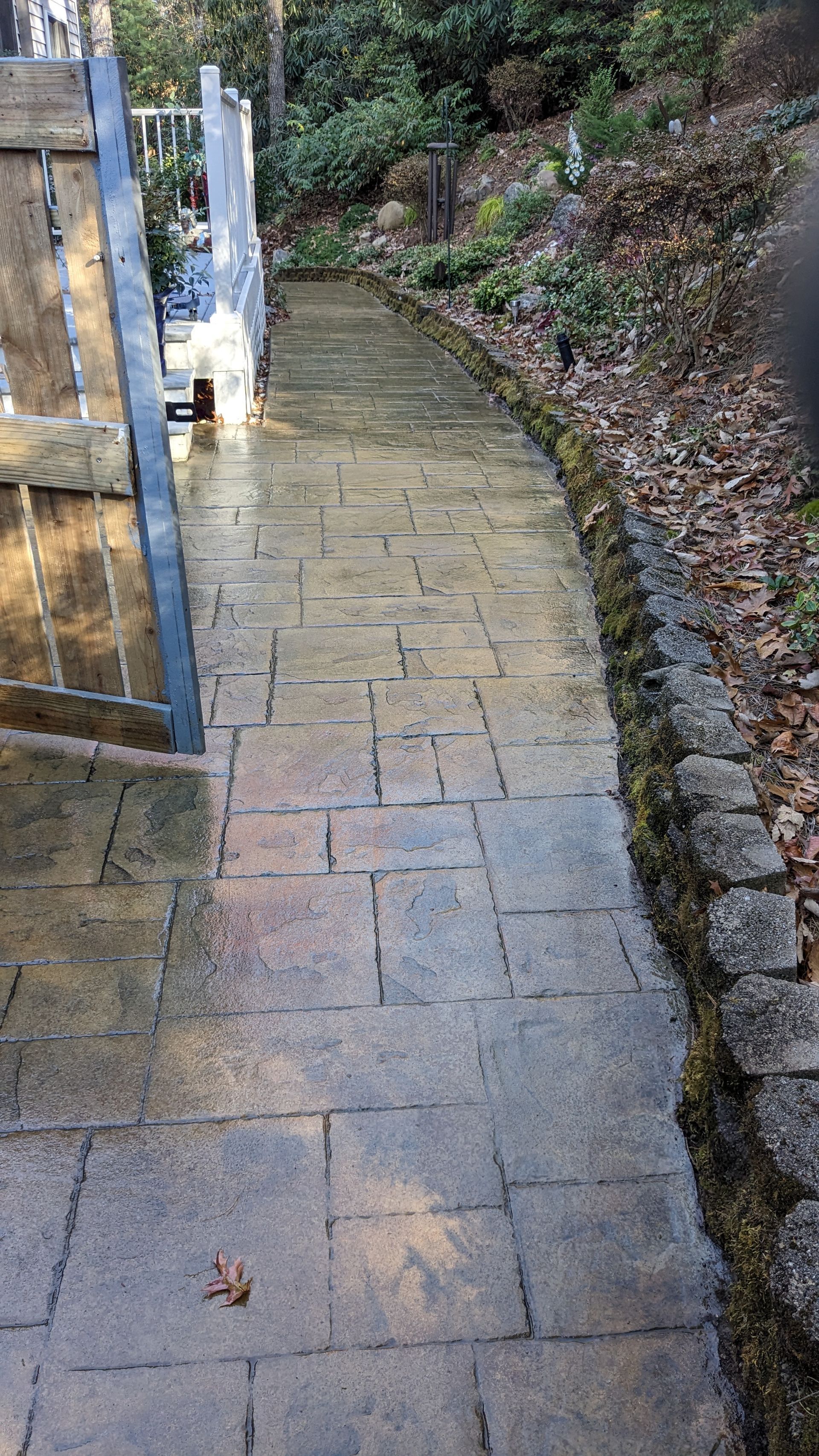 A brick walkway leading to a gate in a garden.