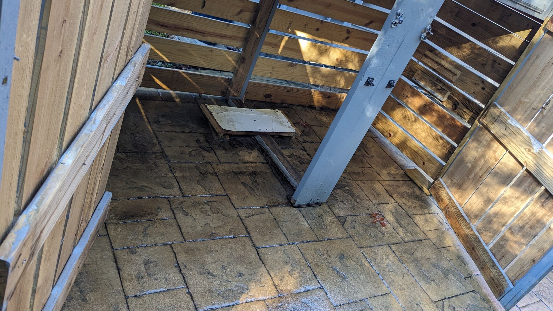 A dirty room with a wooden fence and a concrete floor.