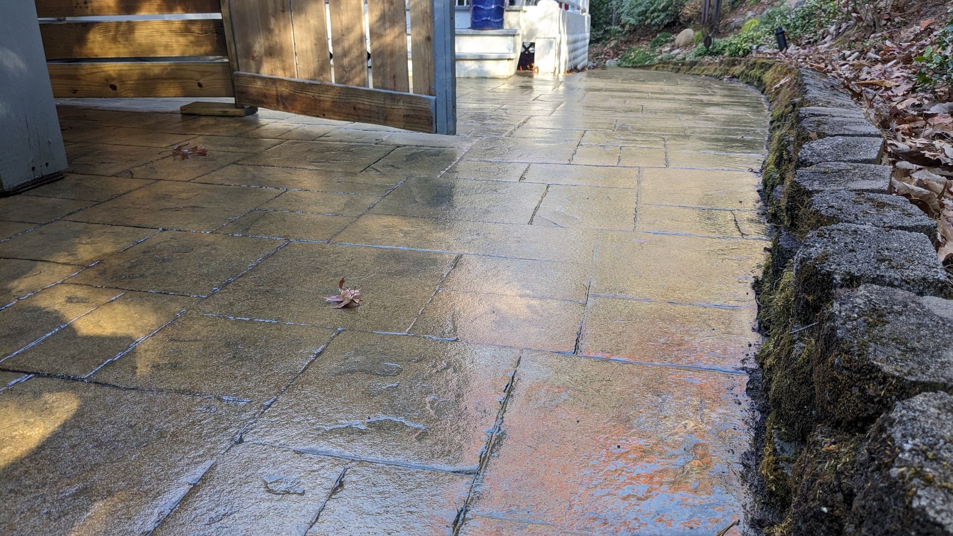A brick walkway with a wooden gate in the background.