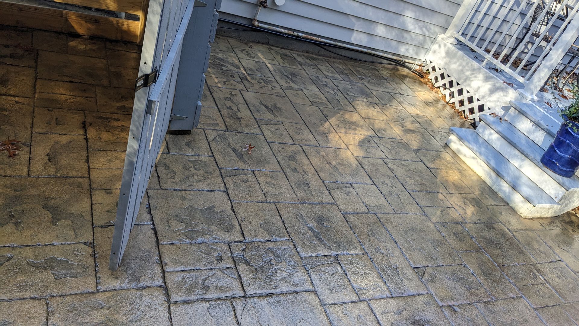 A dirty concrete patio with a chair and stairs in the background.