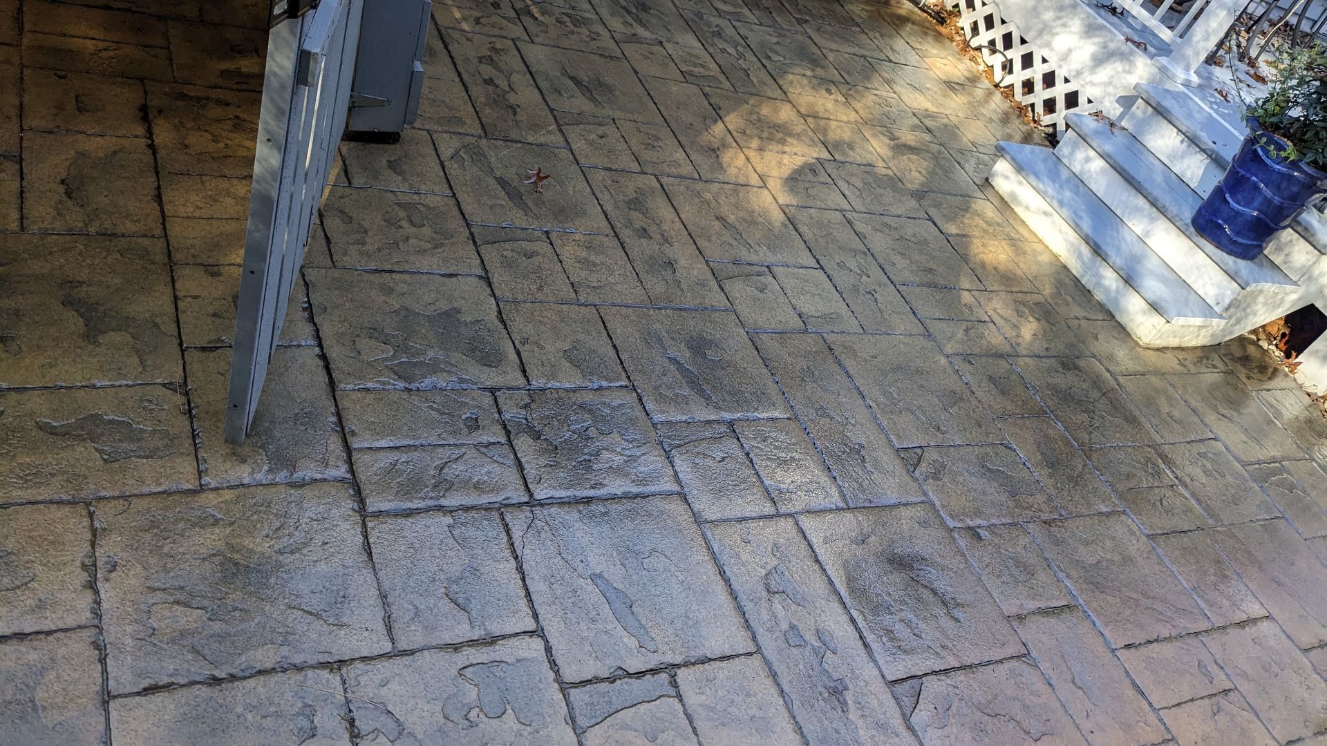 A concrete patio with a chair and stairs in the background.