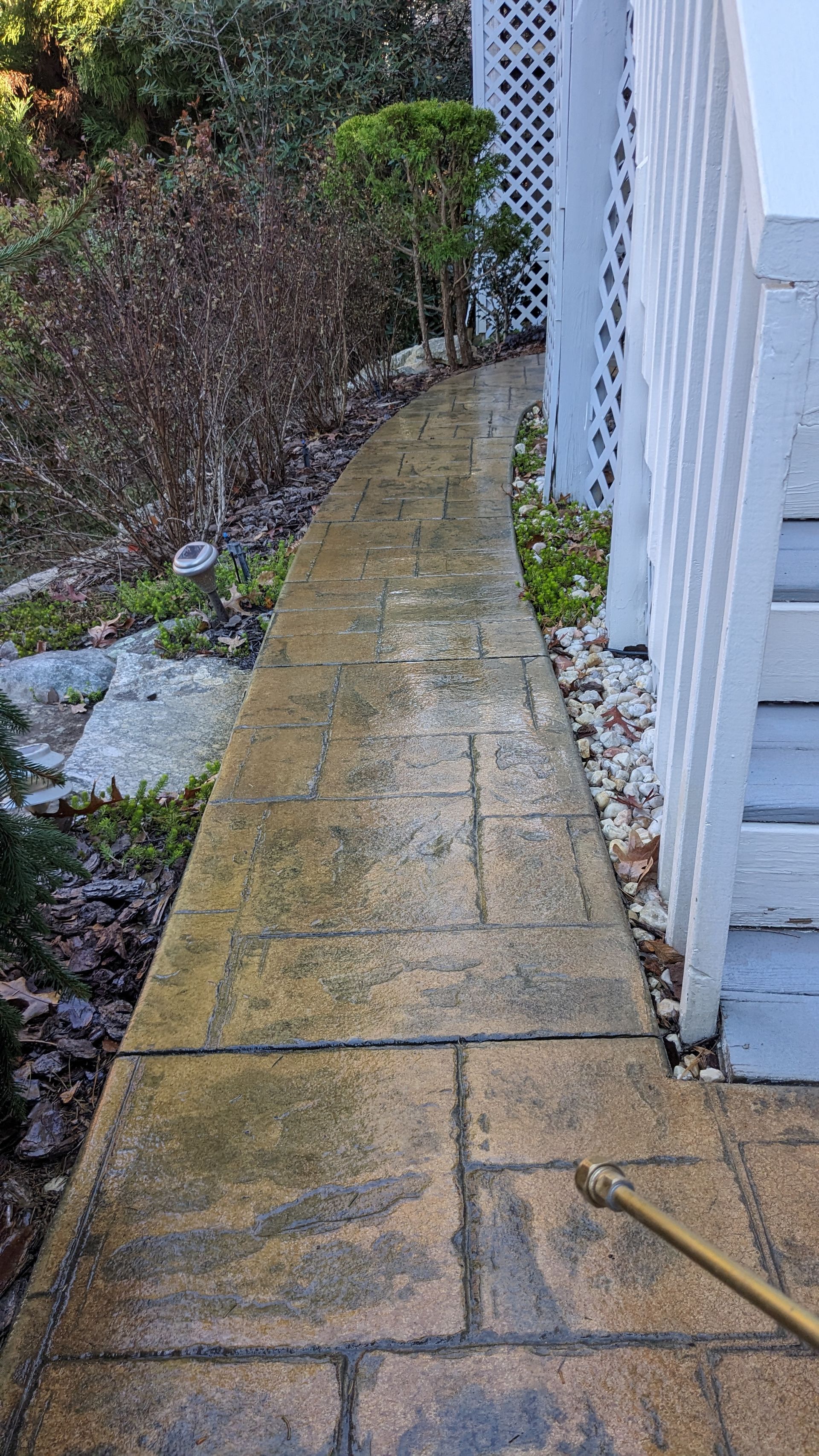 A sidewalk is being cleaned with a pressure washer.