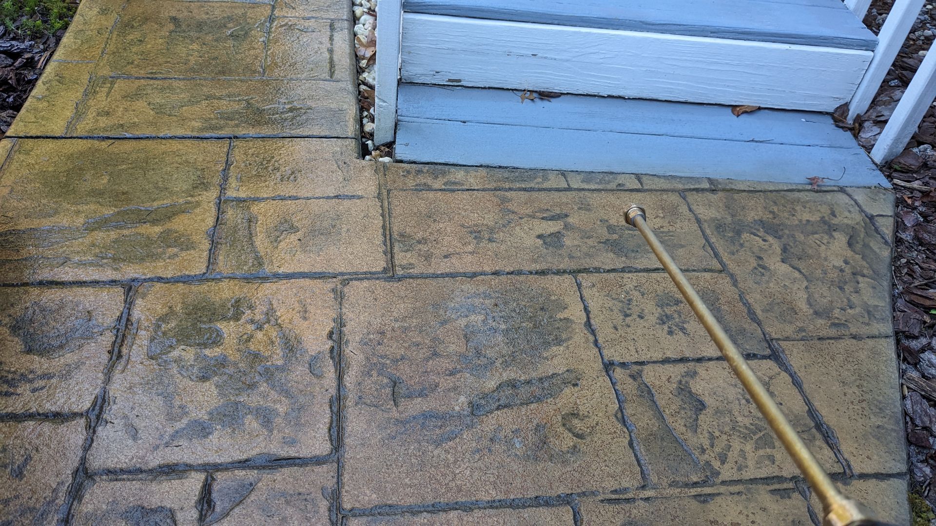 A person is cleaning a sidewalk with a sprayer.
