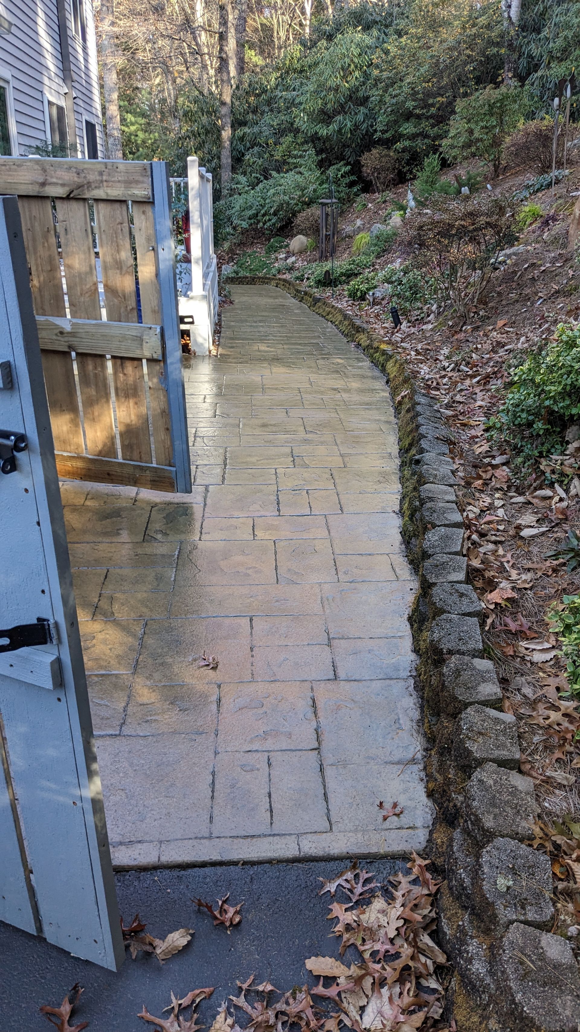 A stone walkway leading to a house with a wooden gate.