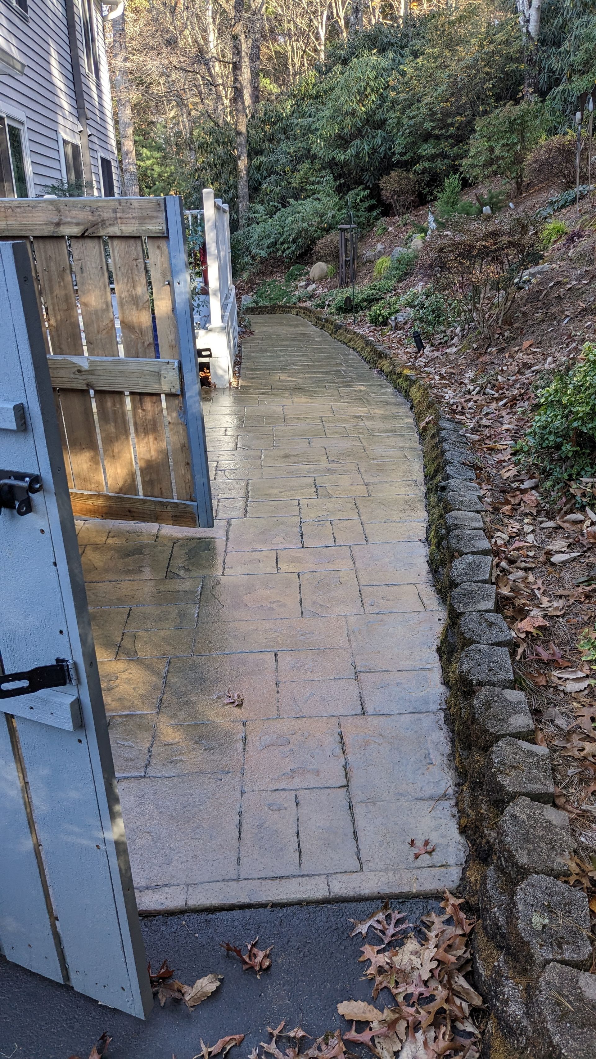 A stone walkway leading to a house with a wooden gate.