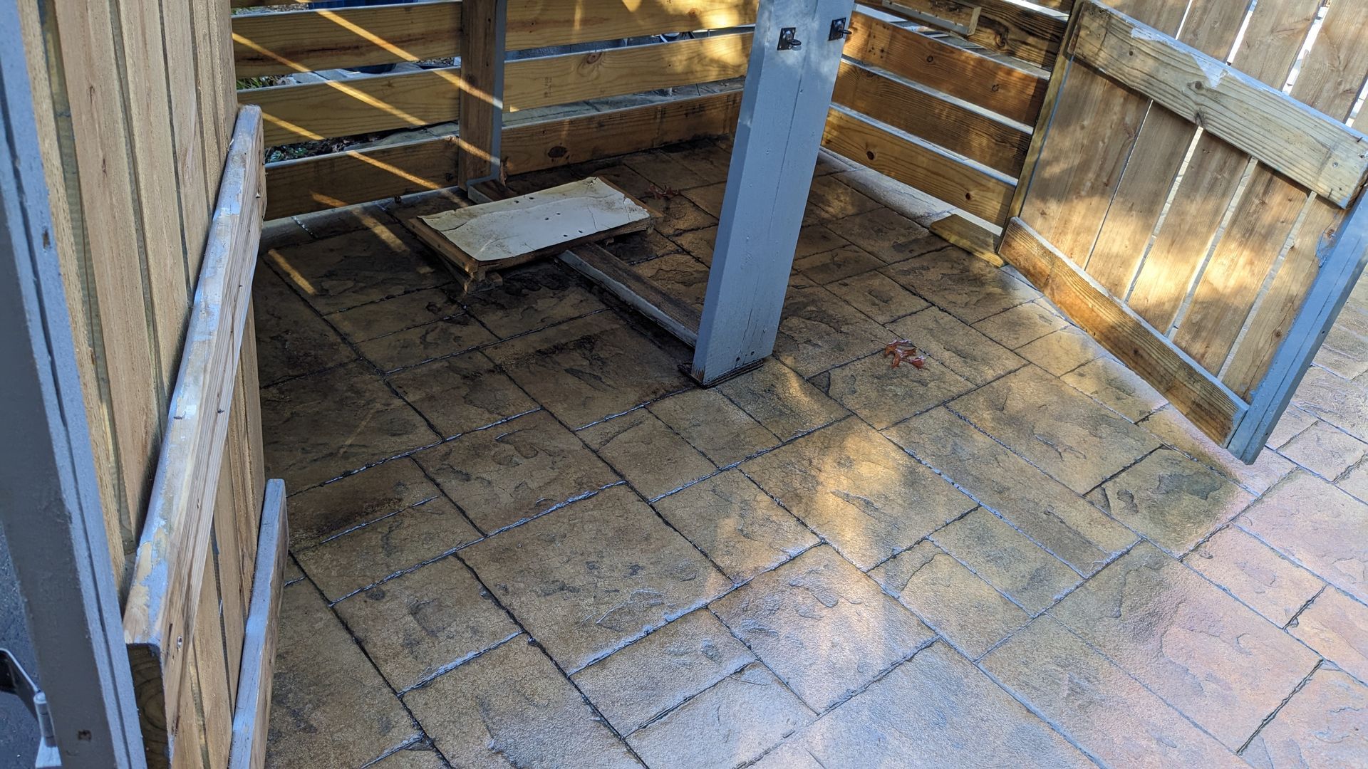 A wooden fence with a brick floor in front of it.