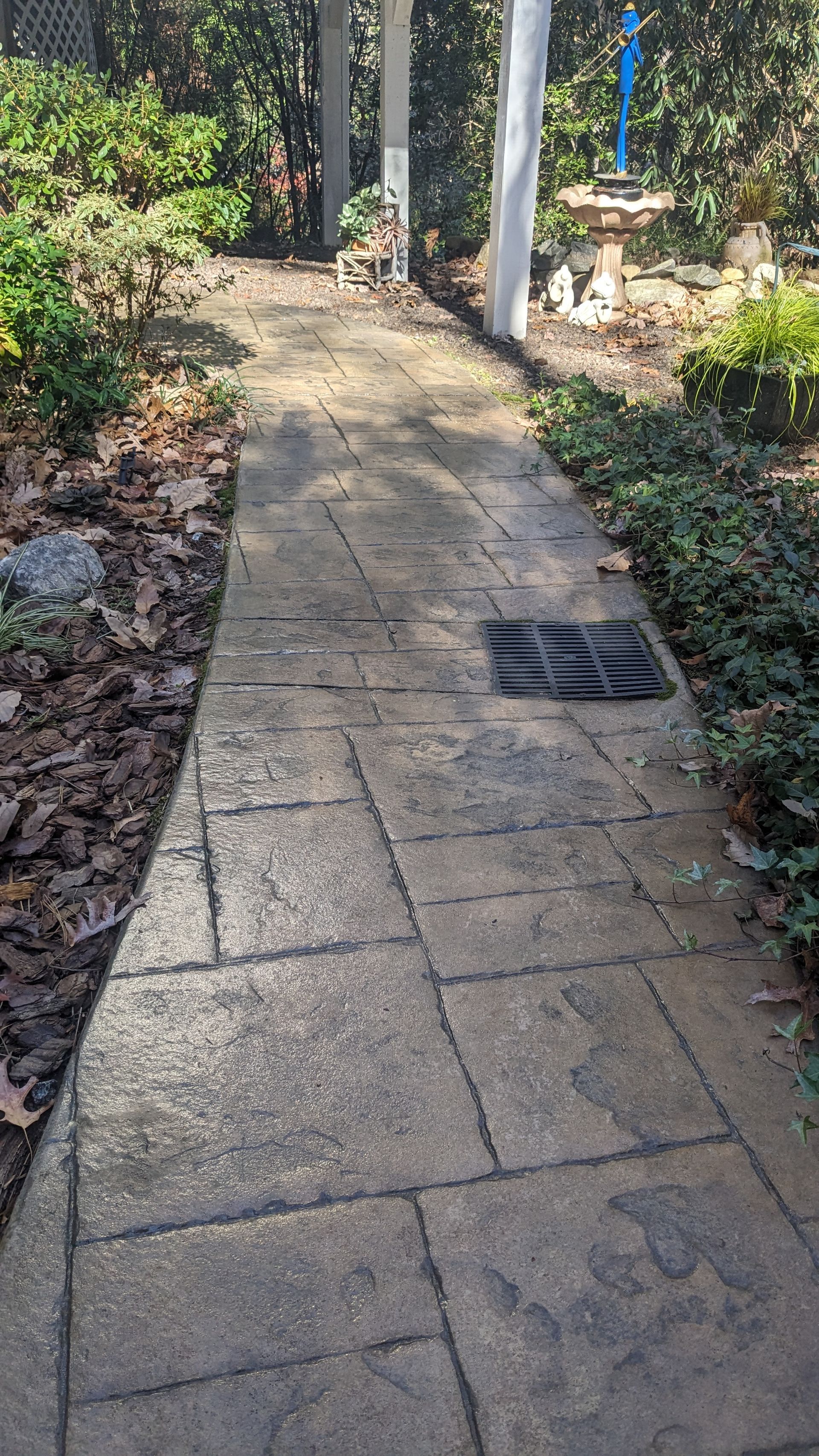 A brick walkway in a park surrounded by trees and bushes.