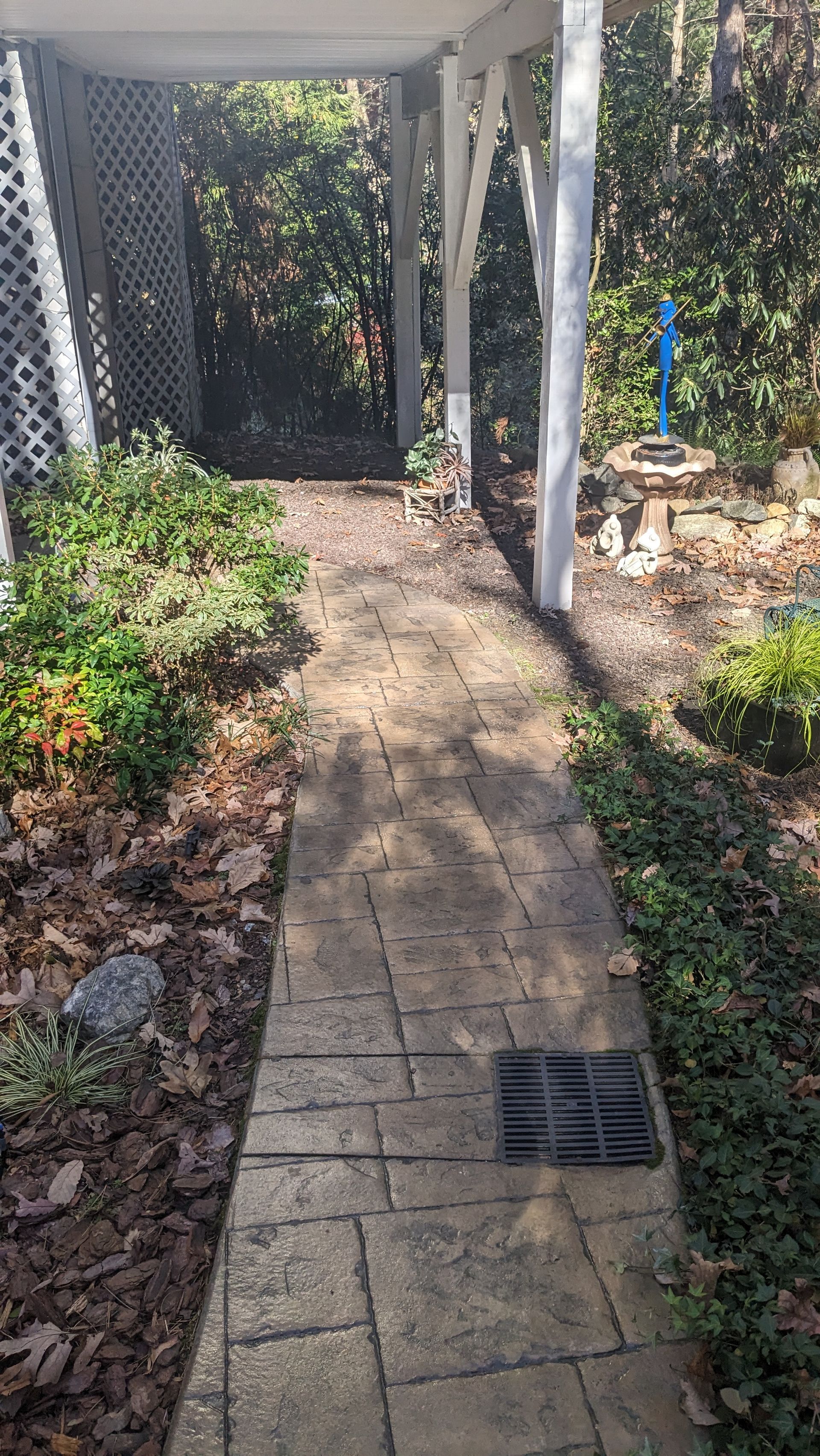 A brick walkway leading to a carport in a garden.