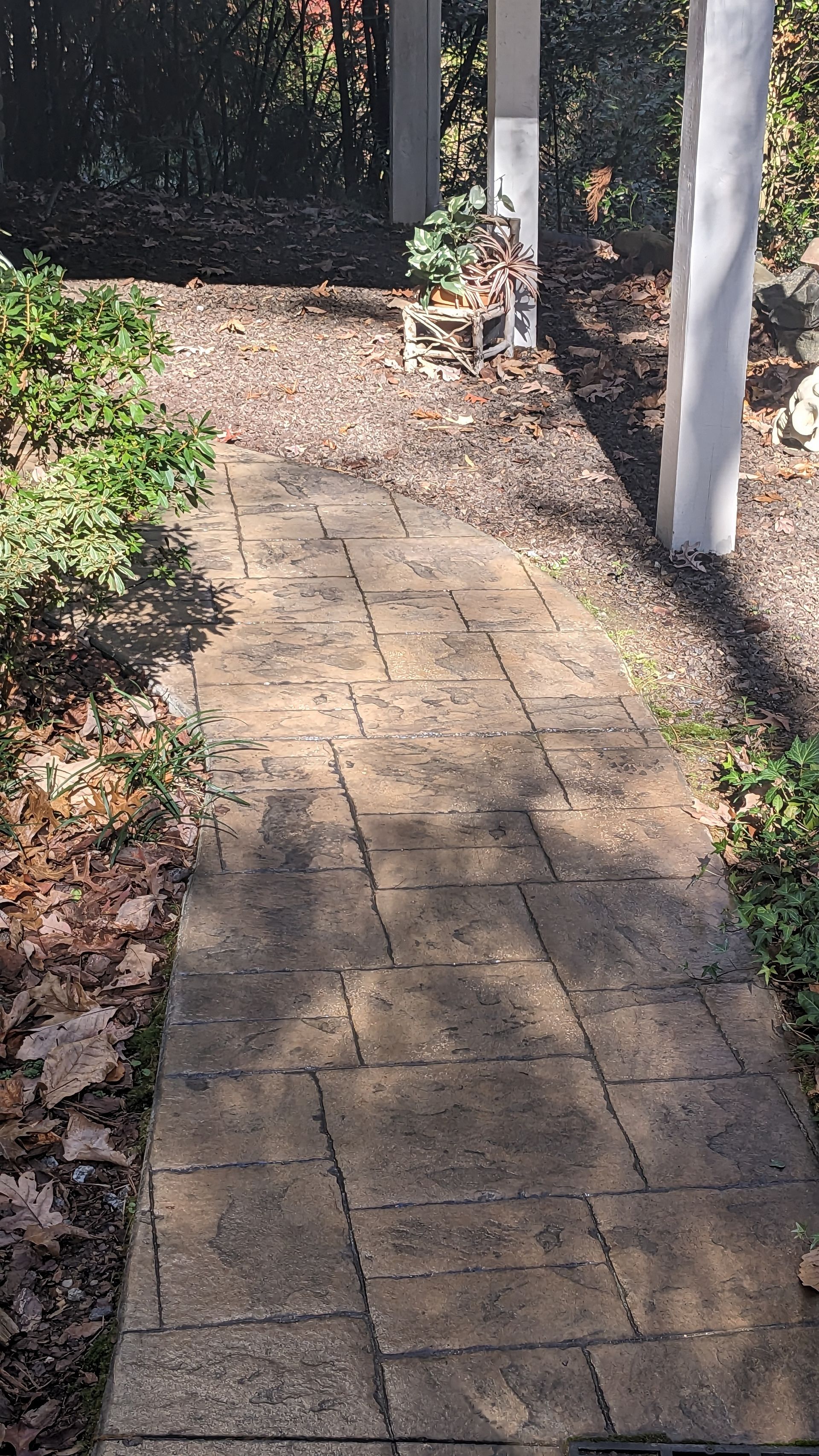 A brick walkway leading to a pergola in a garden.