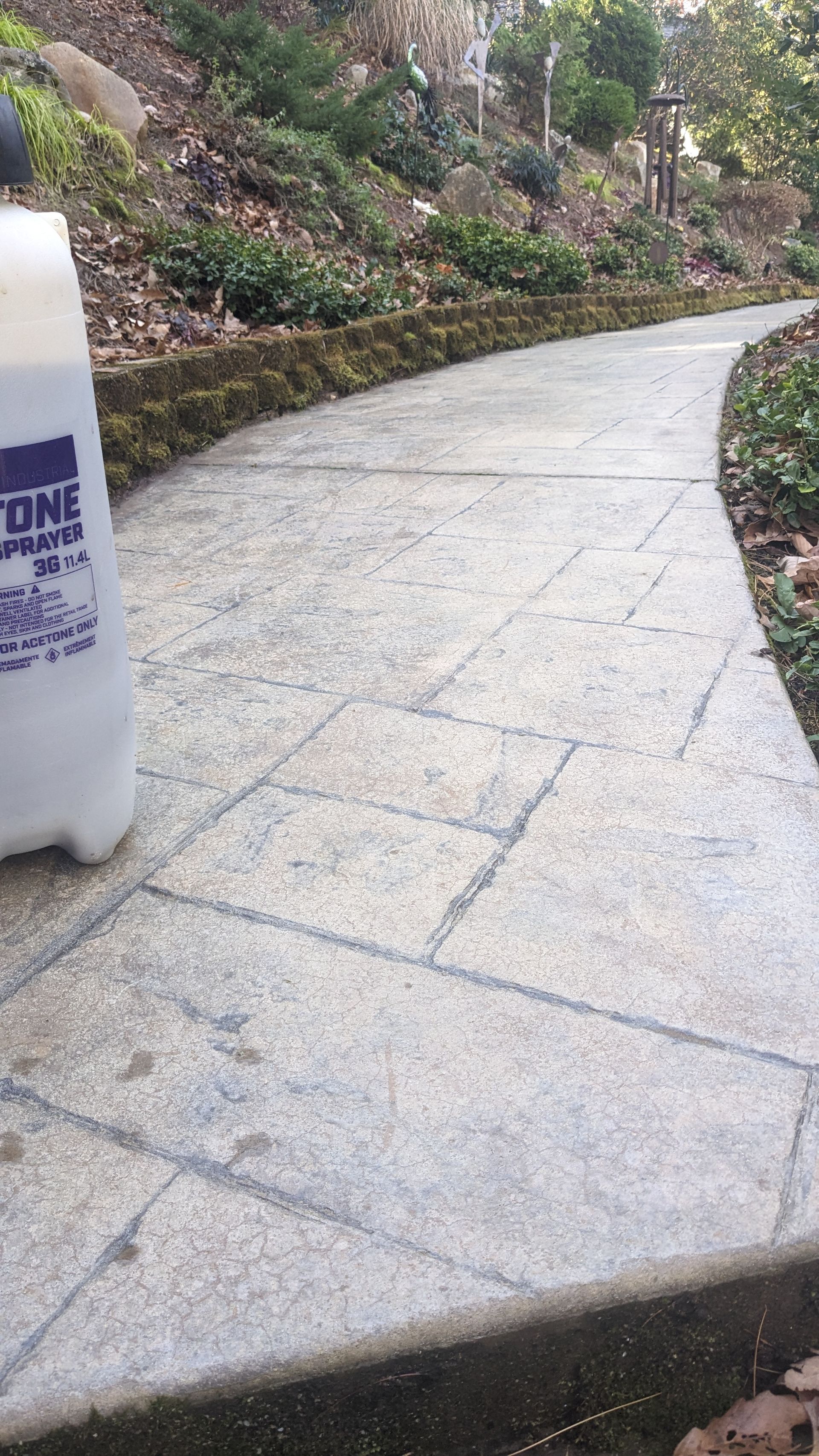 A bottle of water is sitting on the side of a walkway.