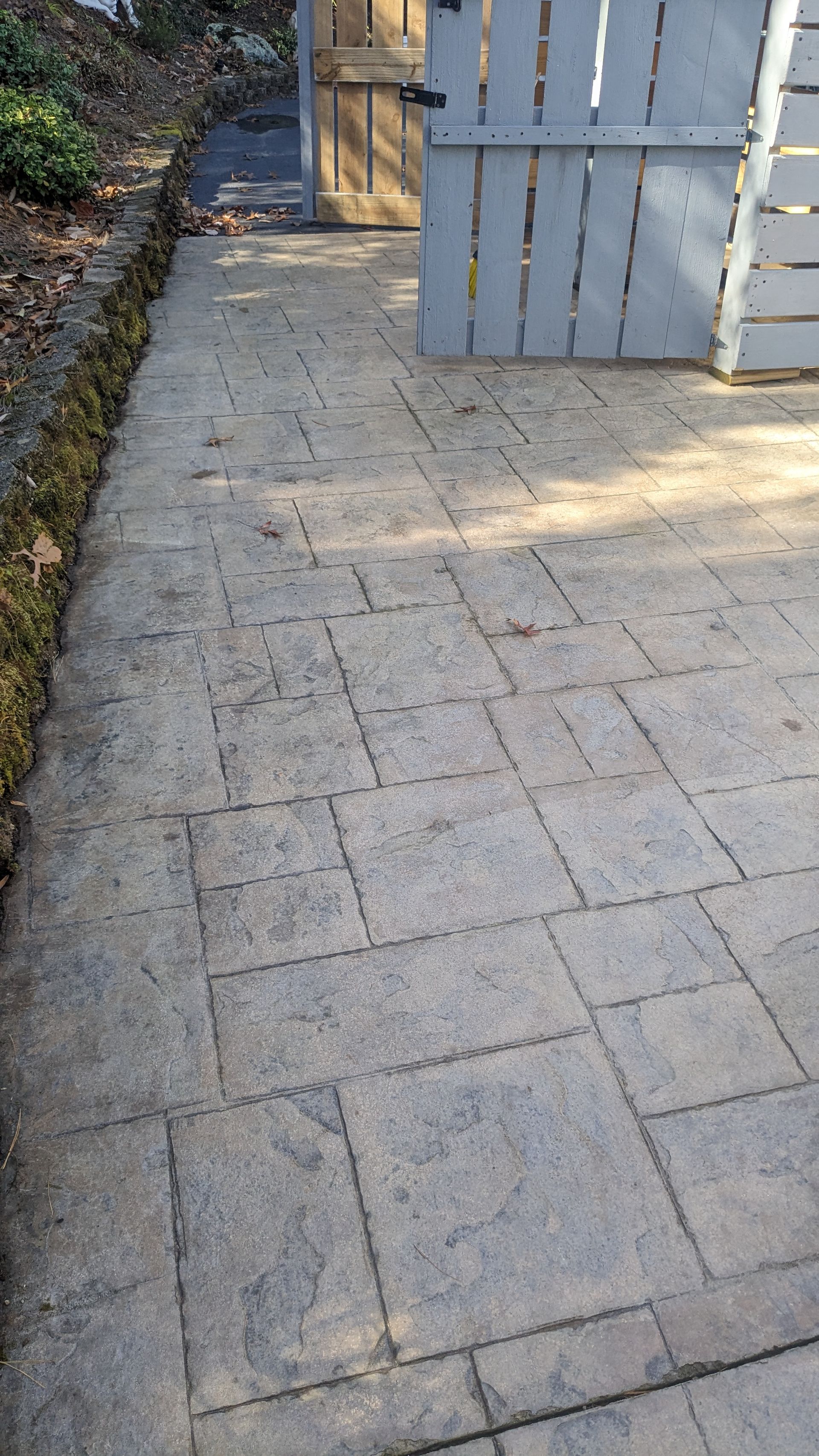 A brick walkway leading to a wooden gate.