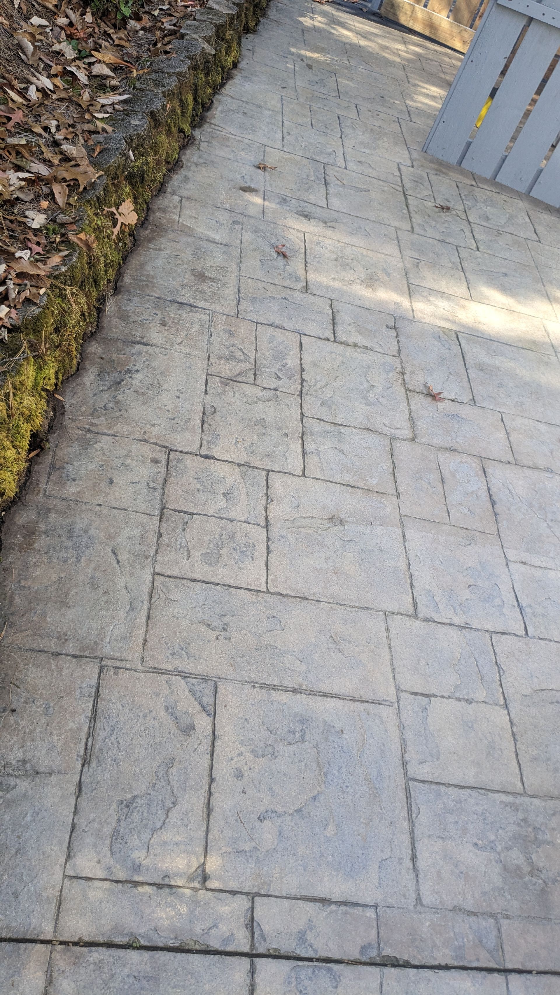 A close up of a brick walkway next to a wooden bench.