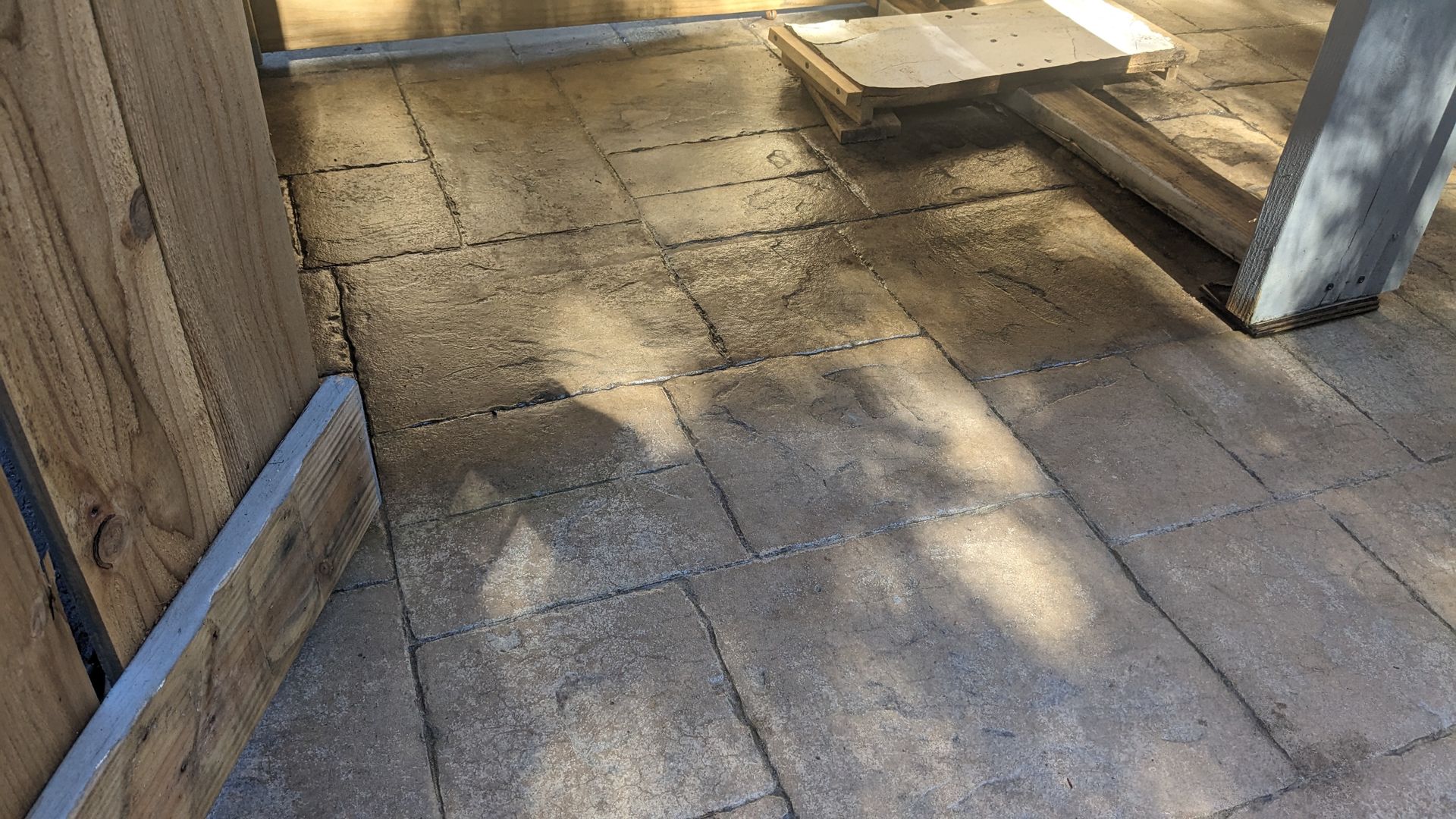 A brick walkway with a wooden fence in the background.