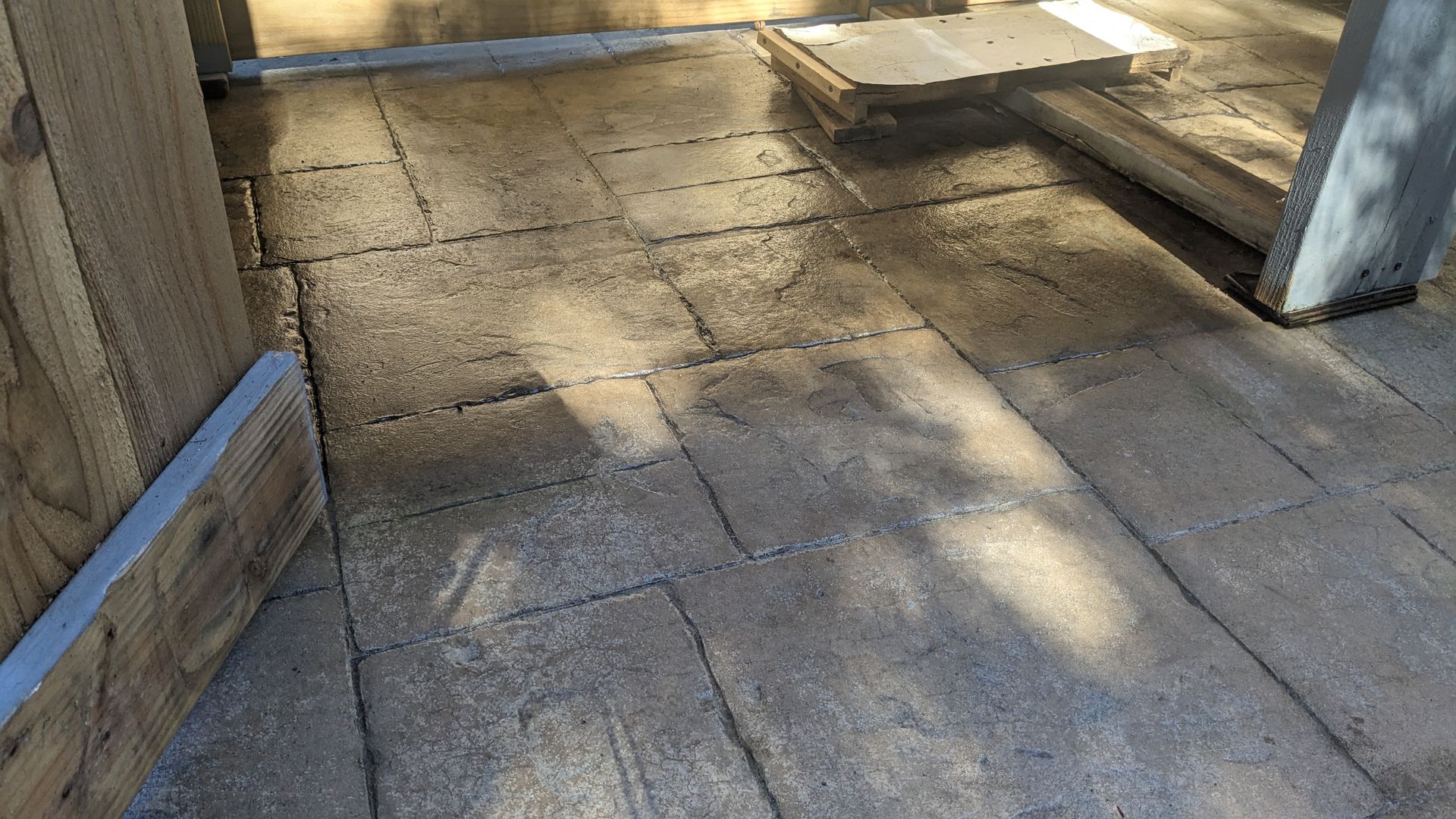 A close up of a brick floor with a wooden fence in the background.