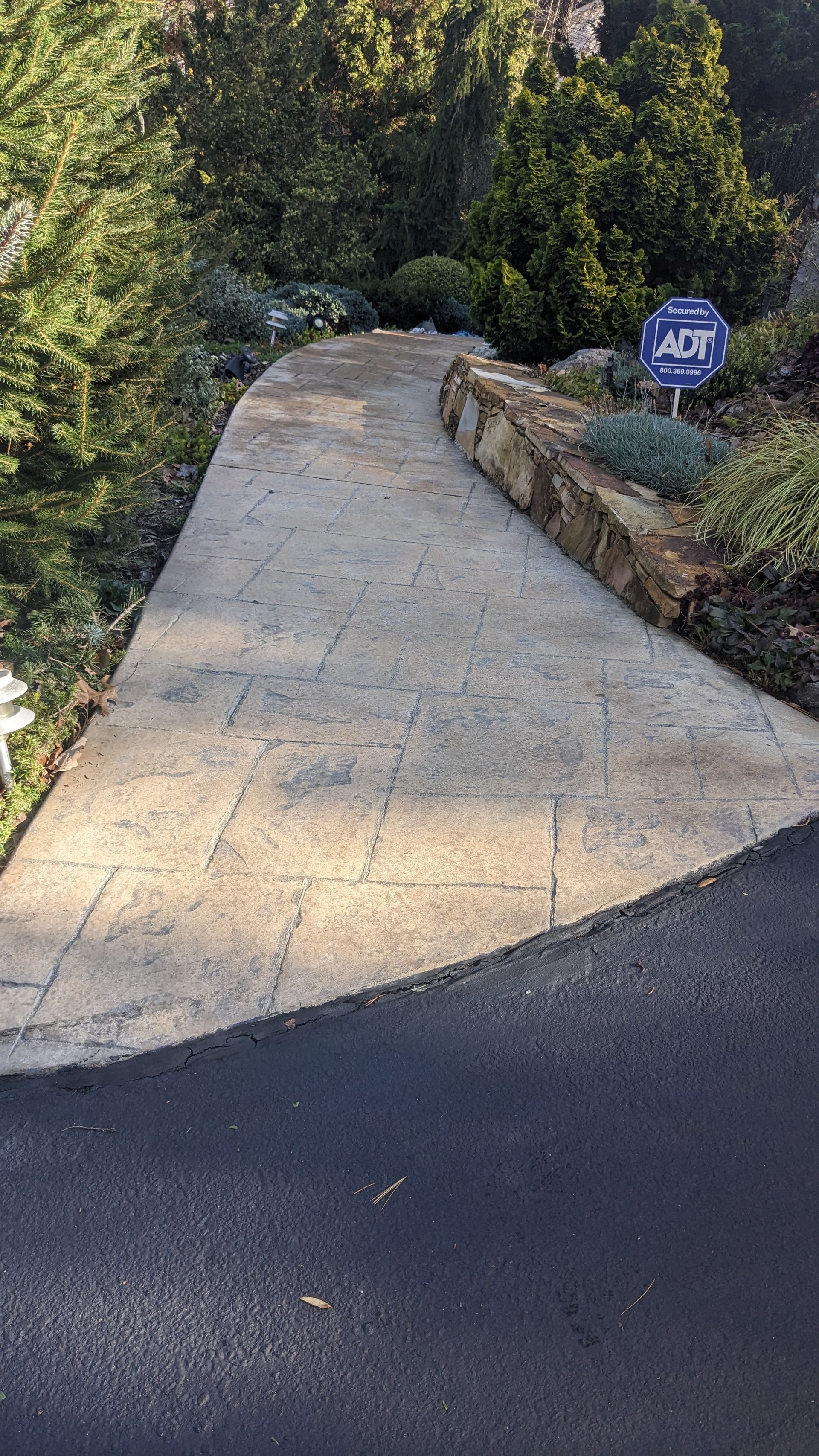 A concrete walkway leading to a house with a sign on the side of it.
