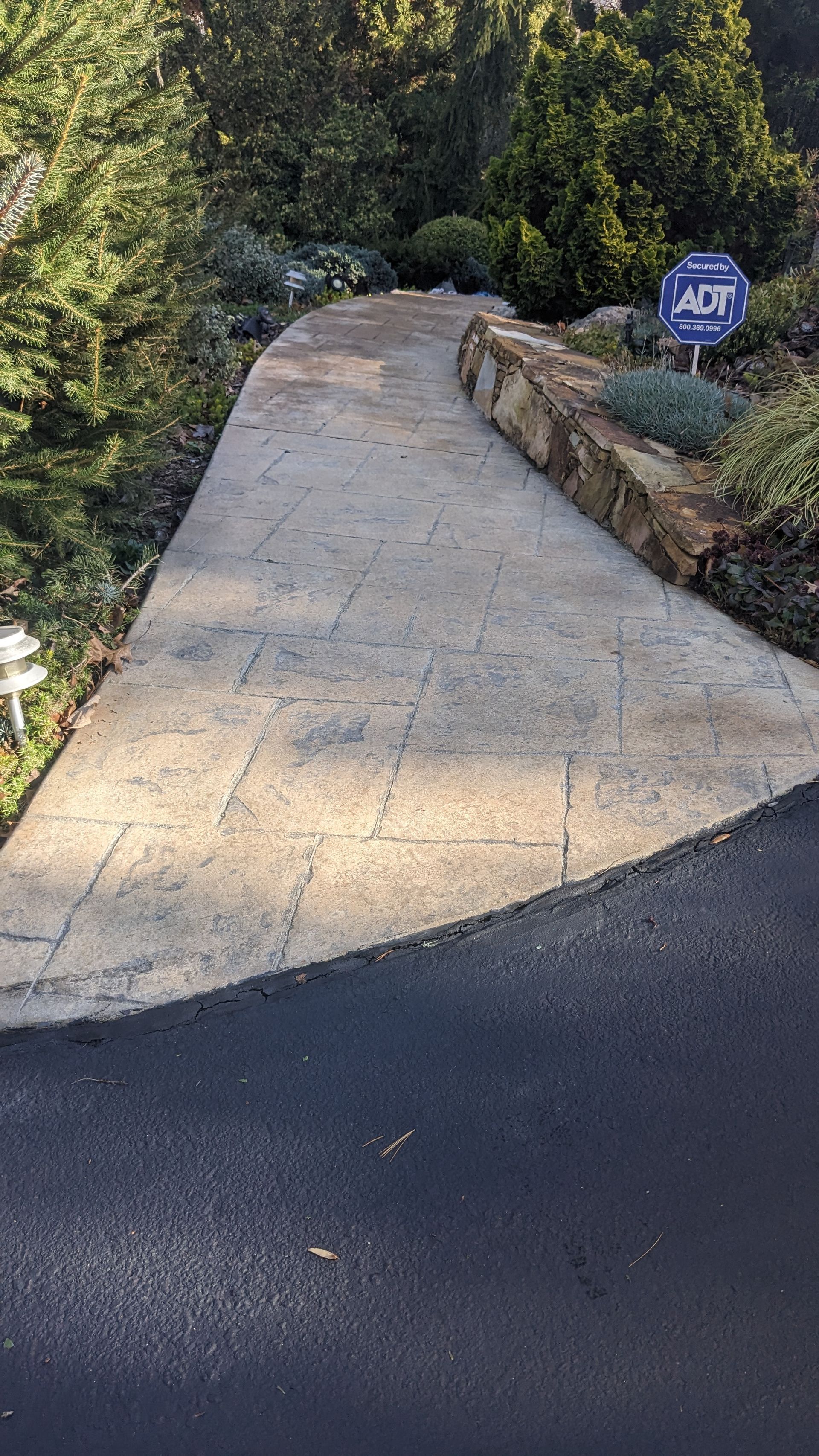A concrete walkway leading to a house with a sign on the side of it.