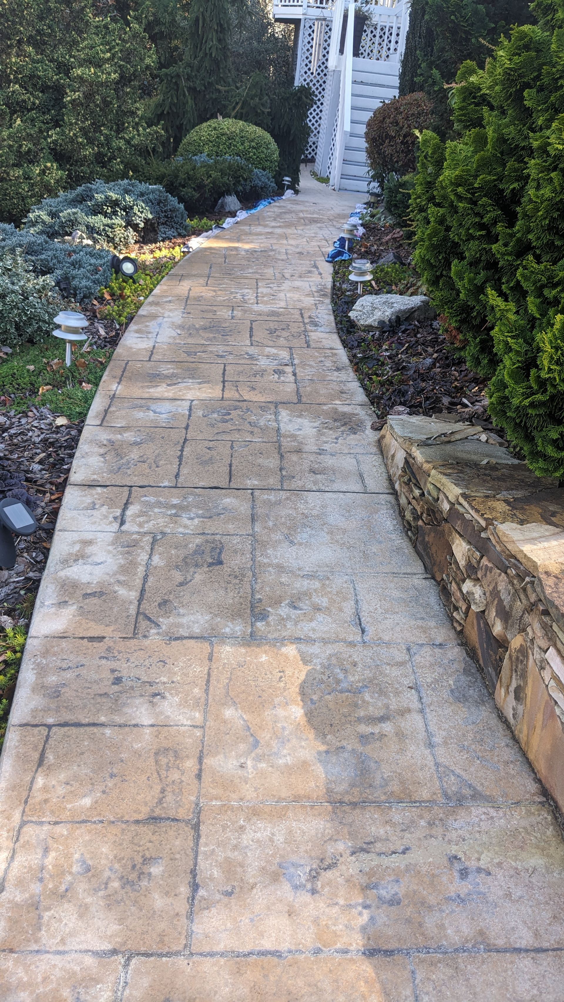A stone walkway leading to a house in a garden.