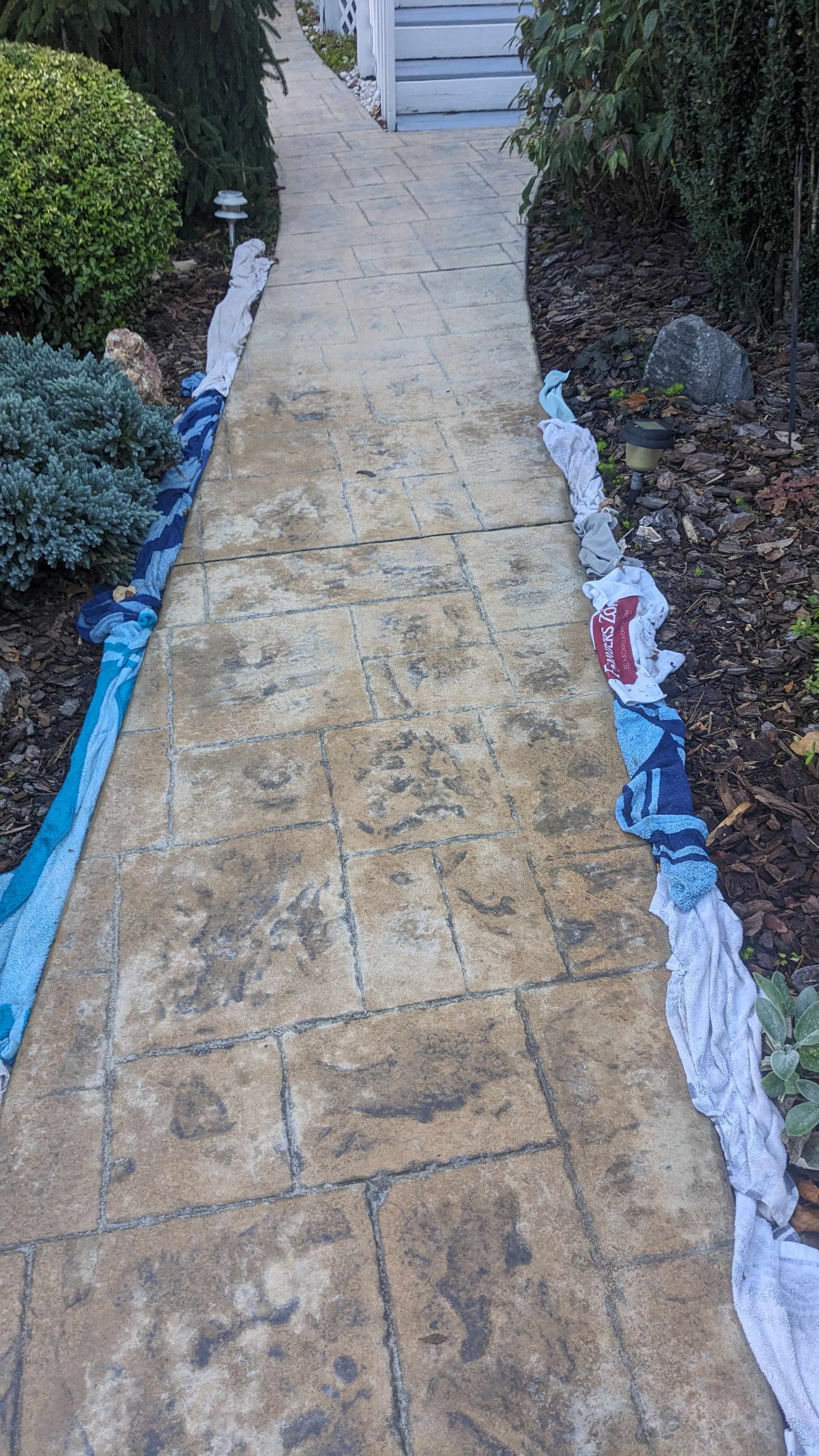 A concrete walkway with a blue tarp on the side of it.
